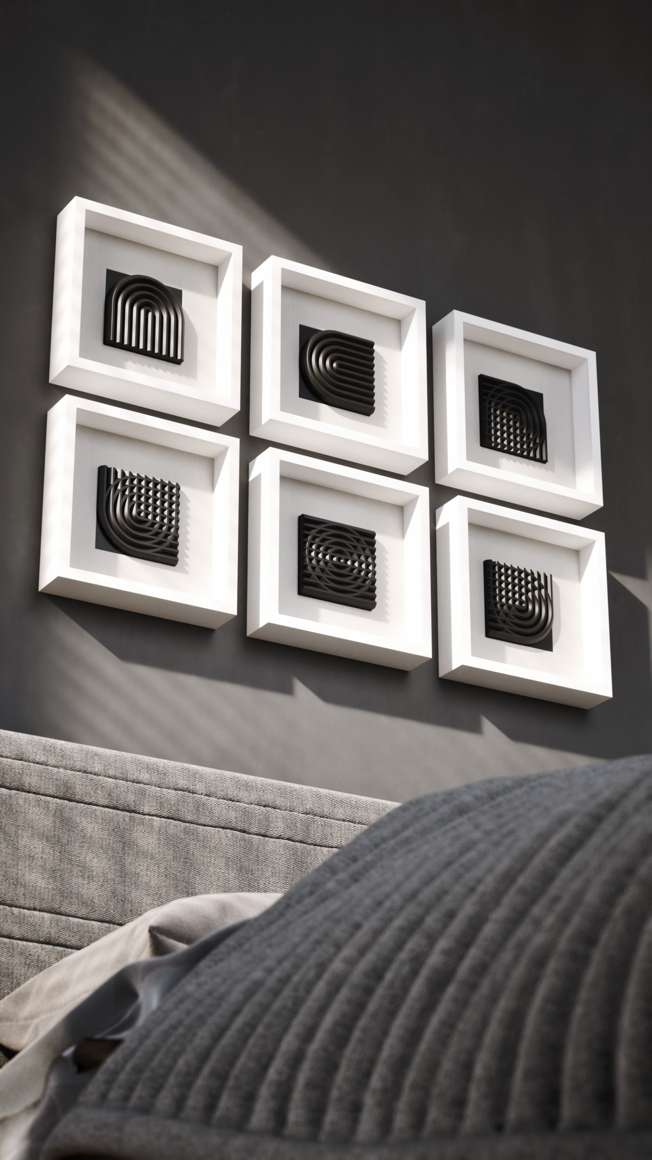 A striking wall installation showcasing a series of matte black geometric sculptures encased in white shadowbox frames. The interplay of light and shadows enhances the three-dimensional depth of the curved and grid-like designs, creating a bold and modern visual statement.