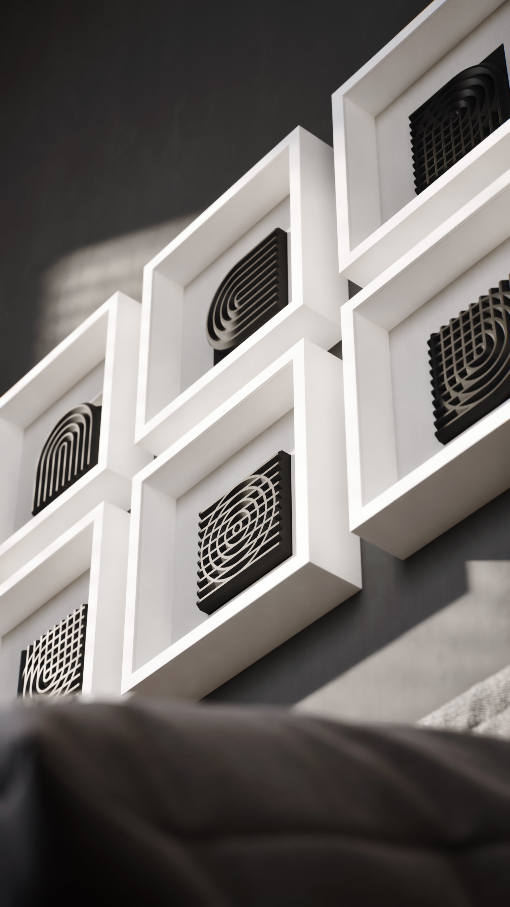 A striking wall installation showcasing a series of matte black geometric sculptures encased in white shadowbox frames. The interplay of light and shadows enhances the three-dimensional depth of the curved and grid-like designs, creating a bold and modern visual statement.