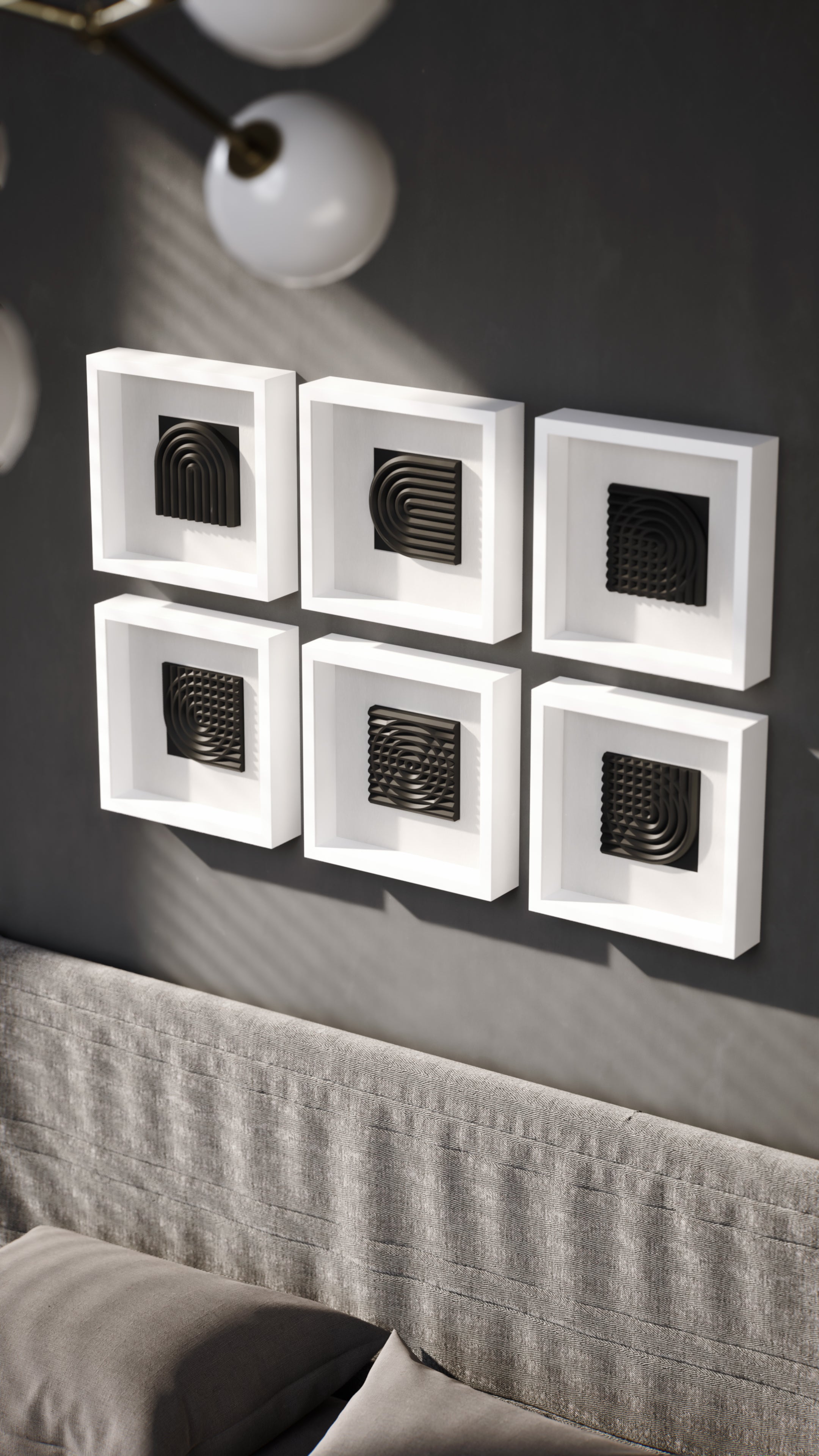 A striking wall installation showcasing a series of matte black geometric sculptures encased in white shadowbox frames. The interplay of light and shadows enhances the three-dimensional depth of the curved and grid-like designs, creating a bold and modern visual statement.