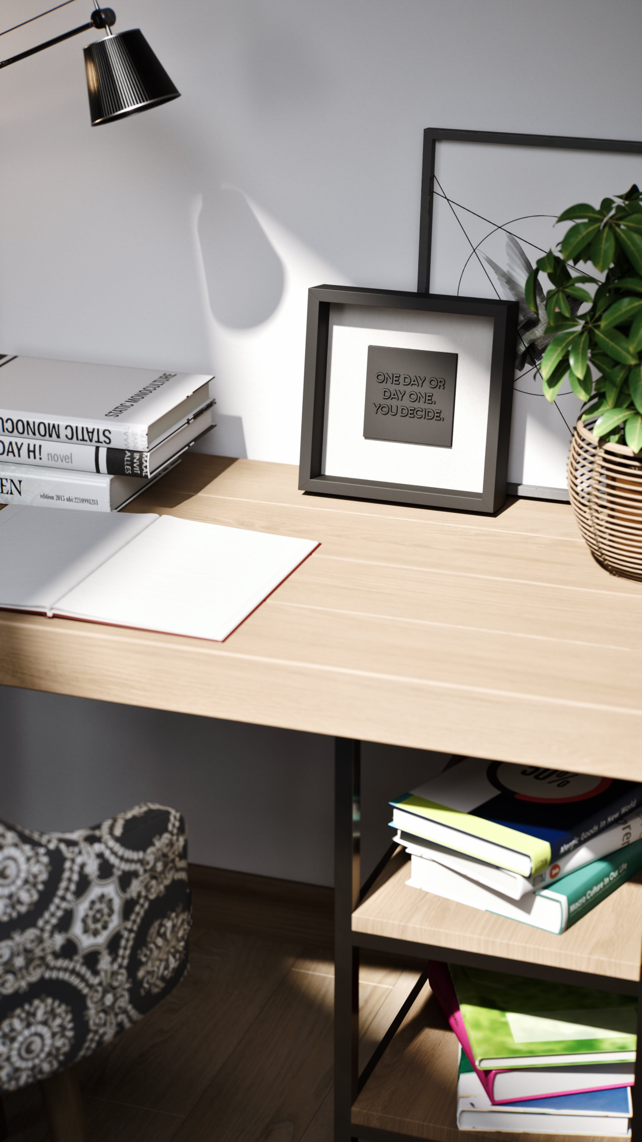 A minimalist desk setup featuring a black shadowbox frame with the motivational quote 'One day or day one. You decide.' The artwork is complemented by neatly stacked books, a wicker plant pot, and geometric wall decor, creating a modern and inspiring workspace.