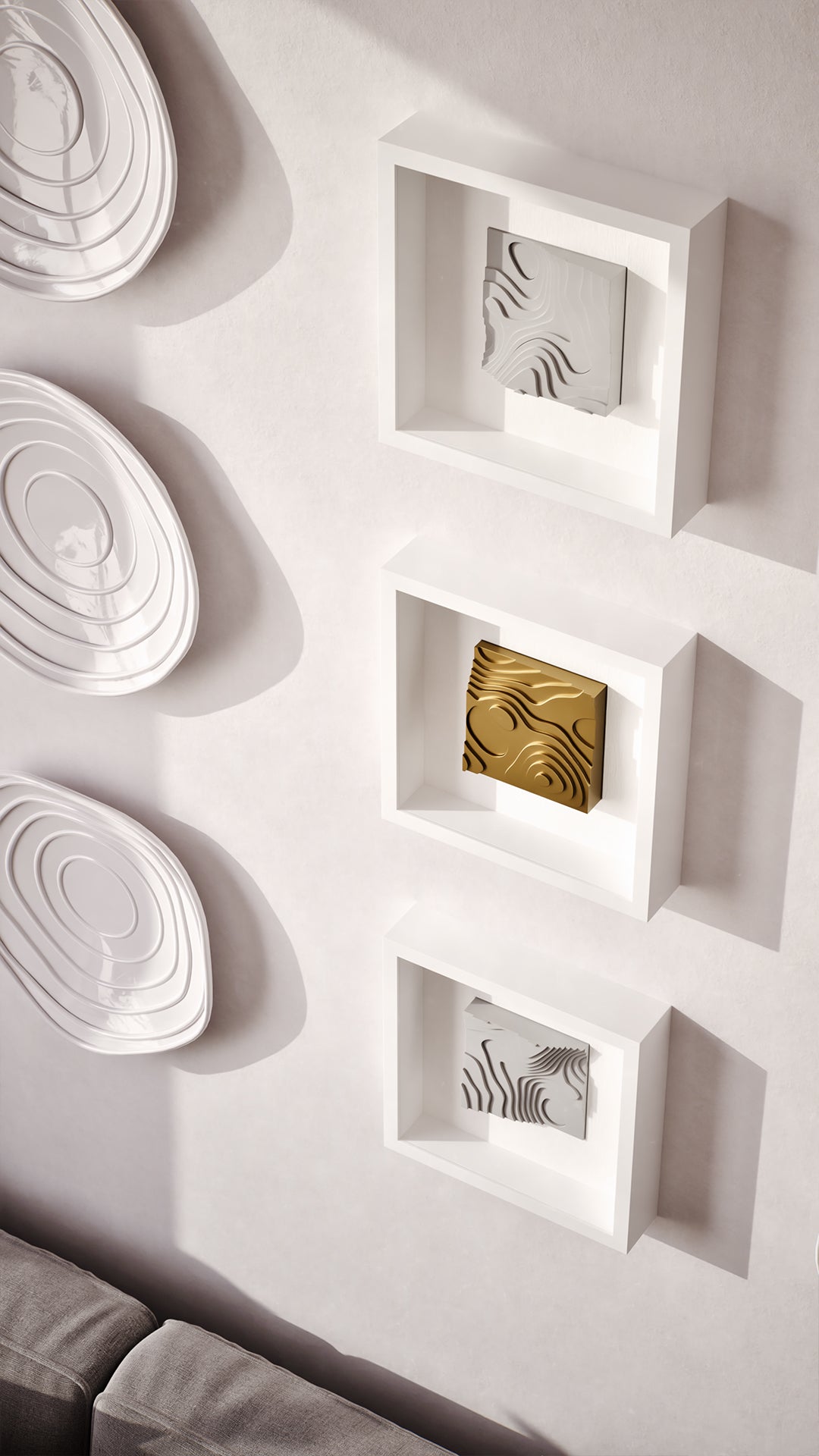 A sophisticated living area featuring a cozy gray sofa adorned with textured cushions and a herringbone throw, set against a wall showcasing a curated arrangement of layered white sculptures and illuminated shadowbox frames. The warm wood accents and soft lighting create a harmonious and inviting atmosphere, complemented by modern furniture and design elements.