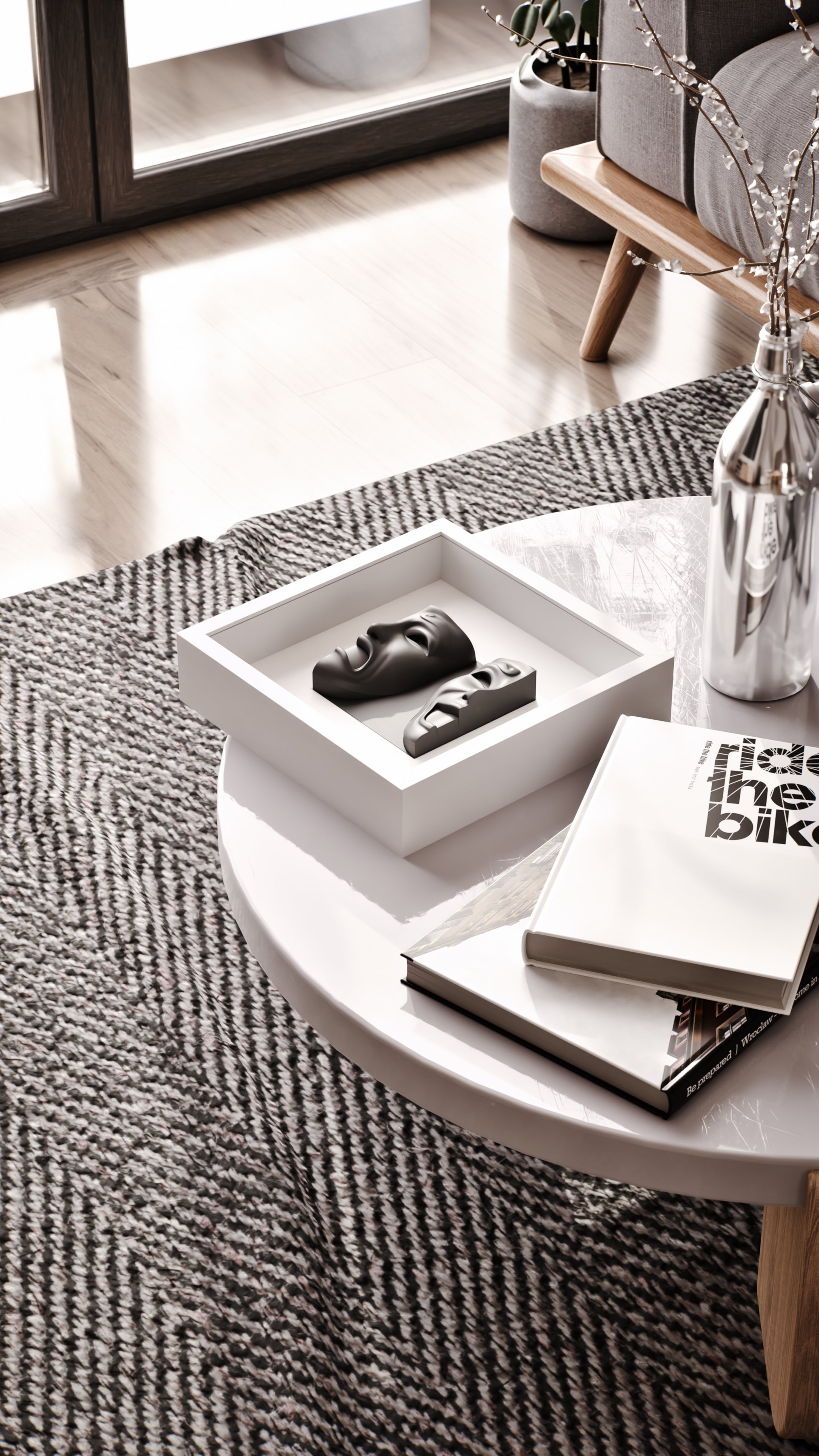 A modern coffee table styled with an elegant display of matte black sculptural pieces in a sleek white shadowbox frame, paired with a selection of contemporary books and a reflective silver vase. The textured herringbone rug and natural light streaming through large windows create a warm and inviting atmosphere.