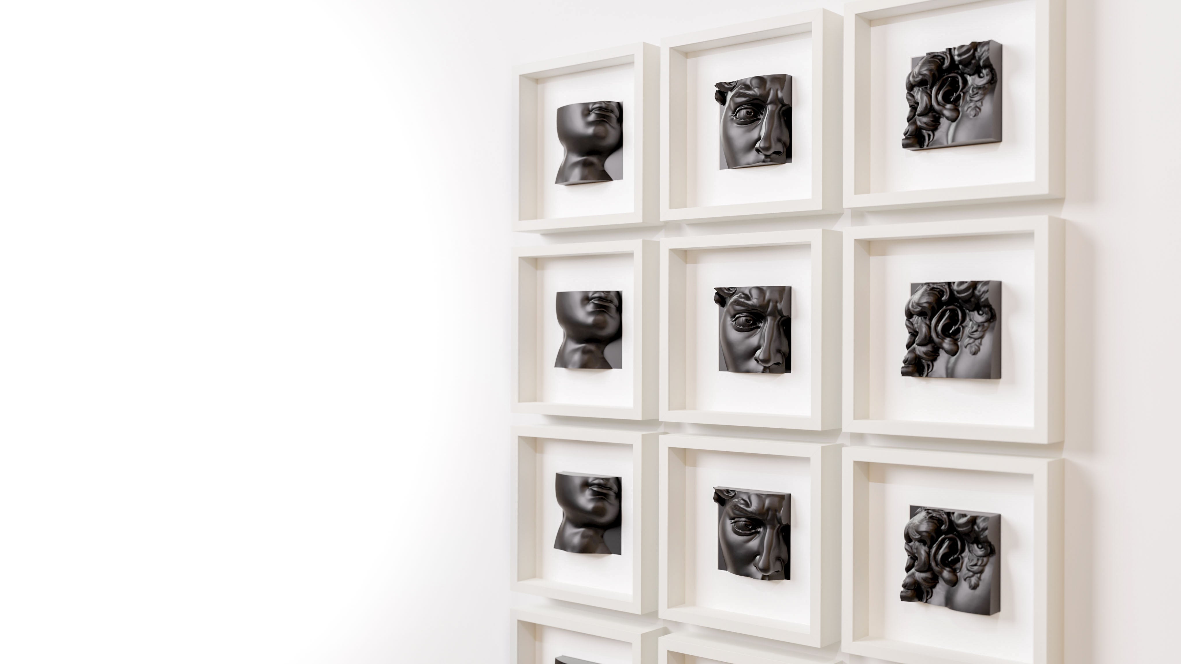 Wall display of white shadowbox frames showcasing a collection of matte black sculptural artworks, each featuring intricate details of classical-inspired designs, arranged in a grid pattern for a cohesive and modern aesthetic.
