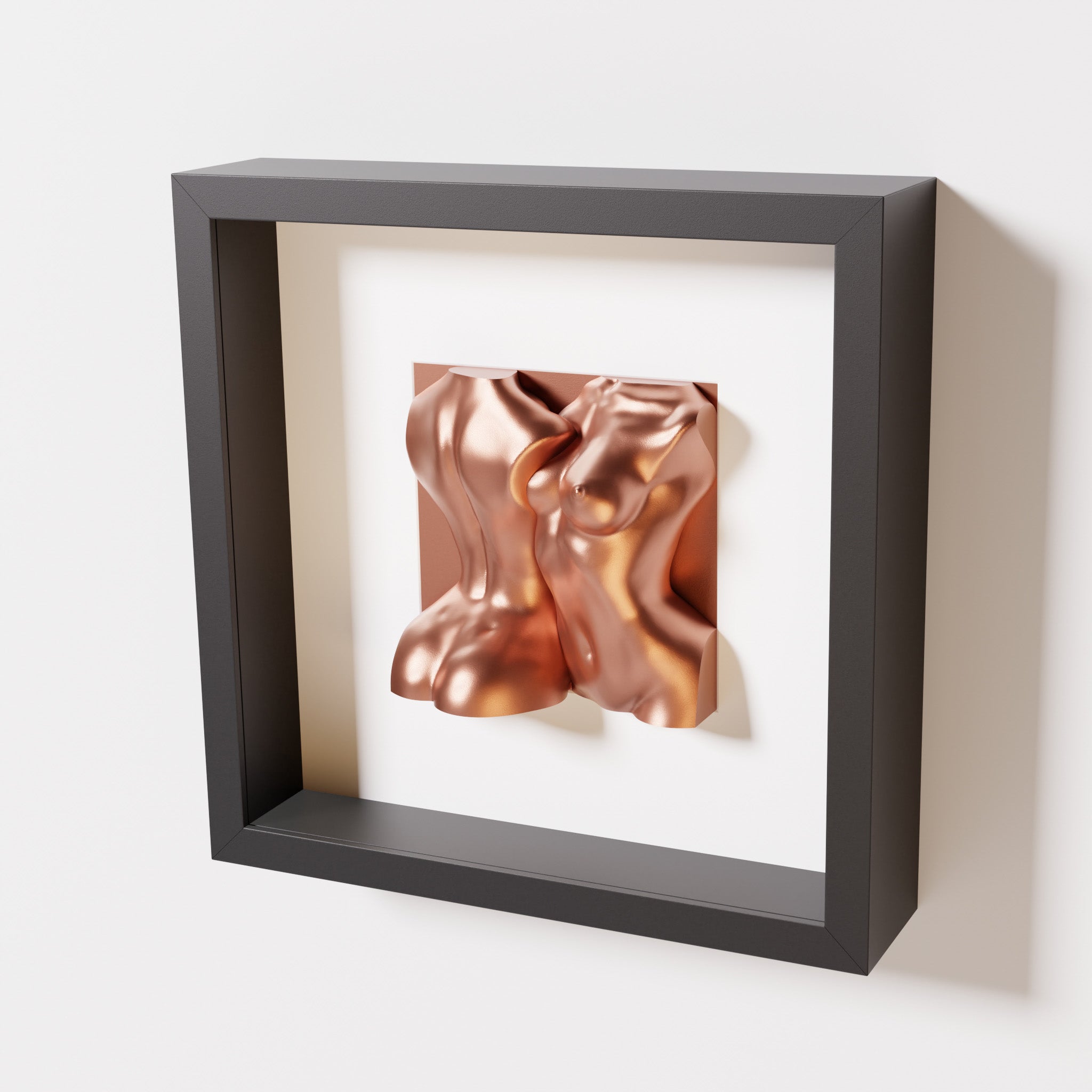 A close-up of a black shadowbox frame containing a chrome copper sculpture of two intertwined female bodies. The reflective copper tones contrast beautifully with the dark frame for a sophisticated look.