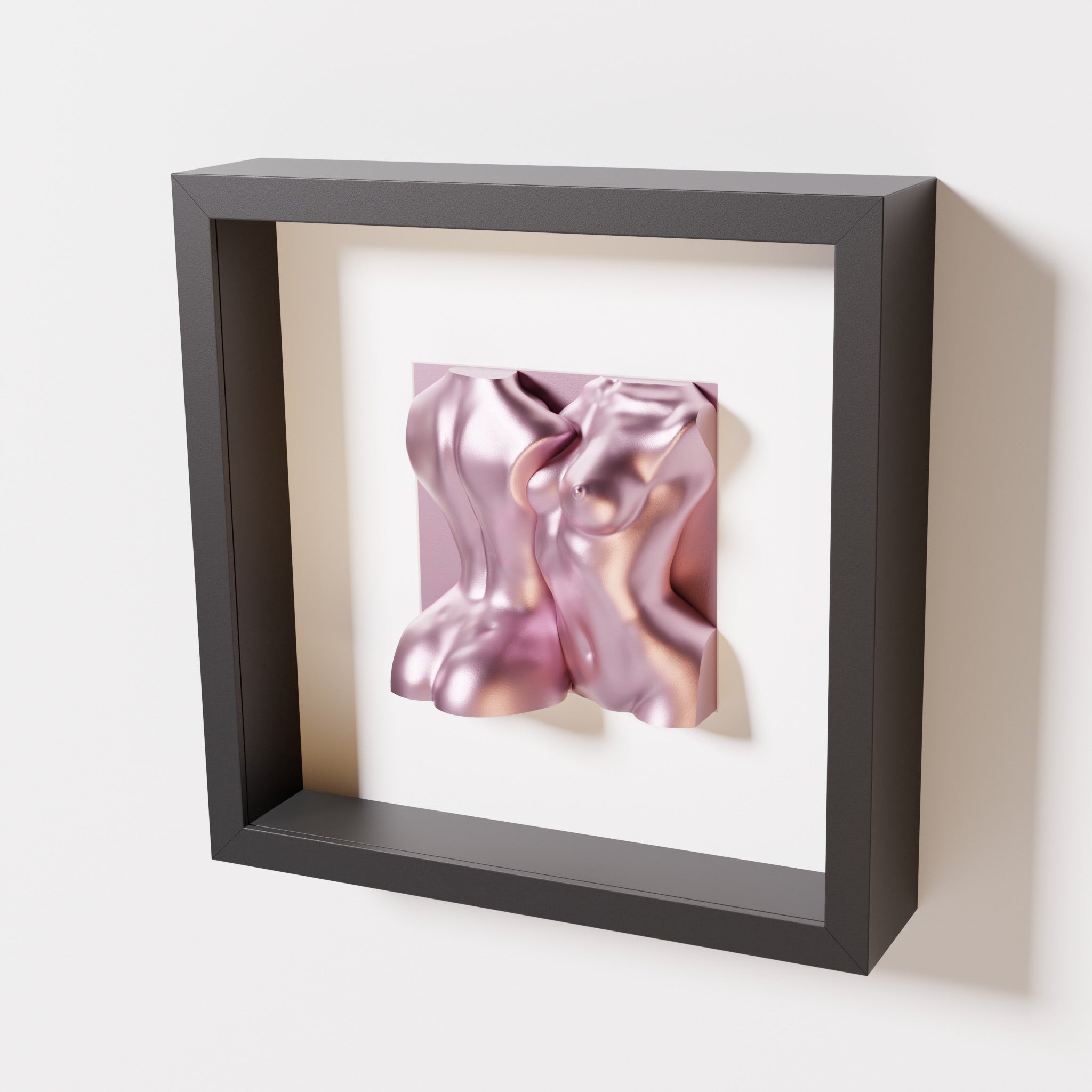 A close-up of a black shadowbox frame containing a metallic rose sculpture of two intertwined female bodies. The reflective pink finish contrasts beautifully with the sleek black frame for a bold, modern look.