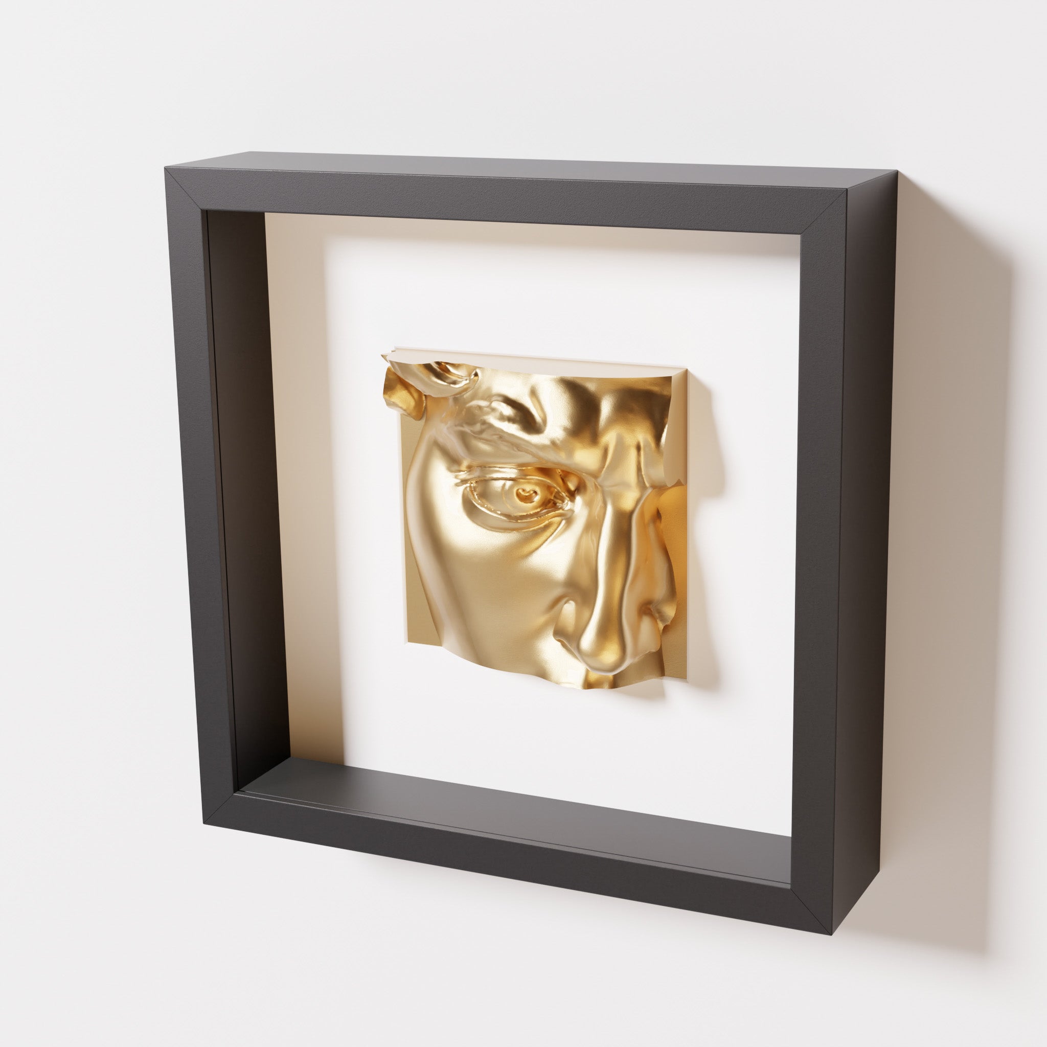 A close-up of a black shadowbox frame containing a chrome gold sculpture of 'David's Eye,' highlighting the intricate details of the eye, brow, and surrounding textures.