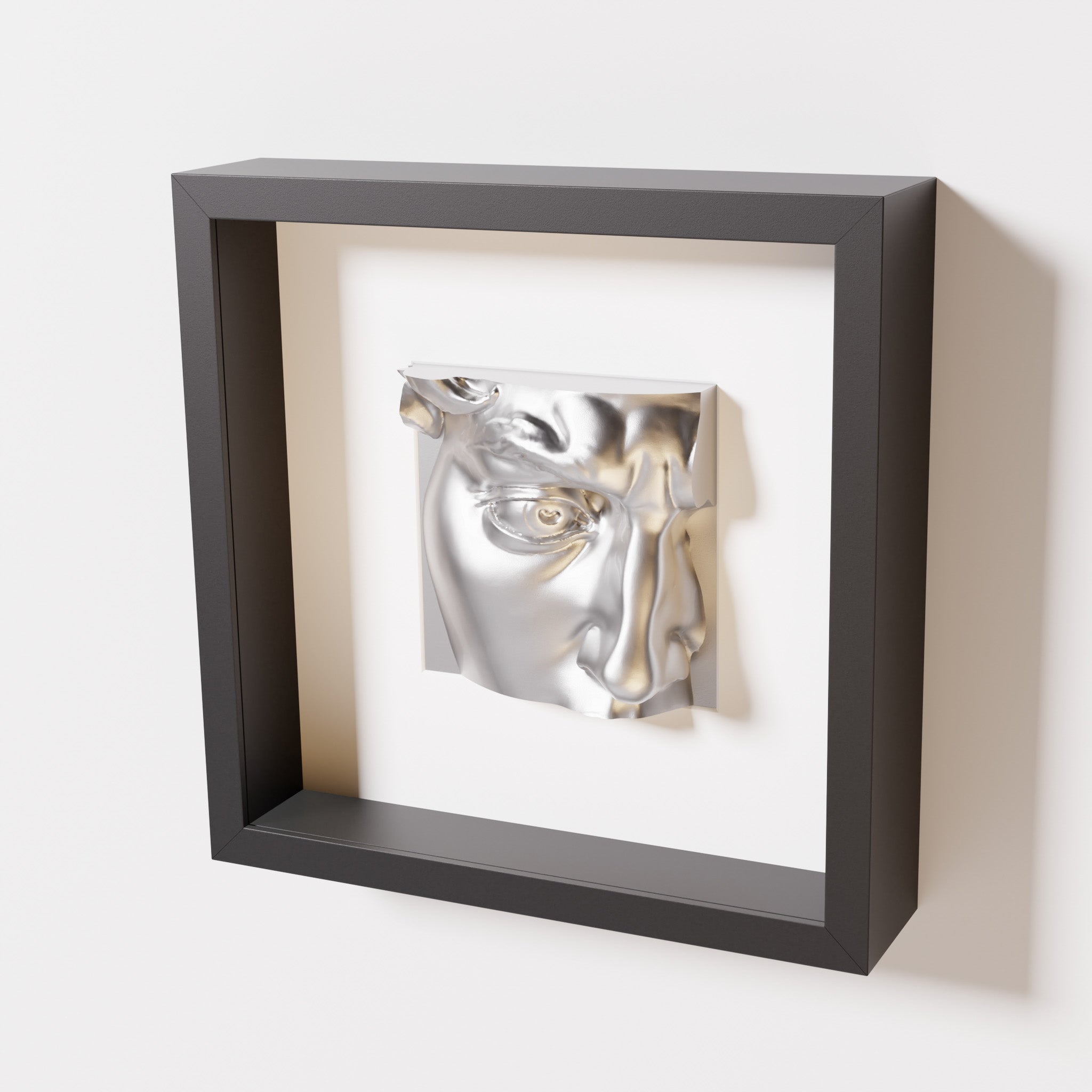 A close-up of a black shadowbox frame containing a chrome silver sculpture of 'David's Eye,' highlighting the intricate details of the eye, brow, and surrounding textures.