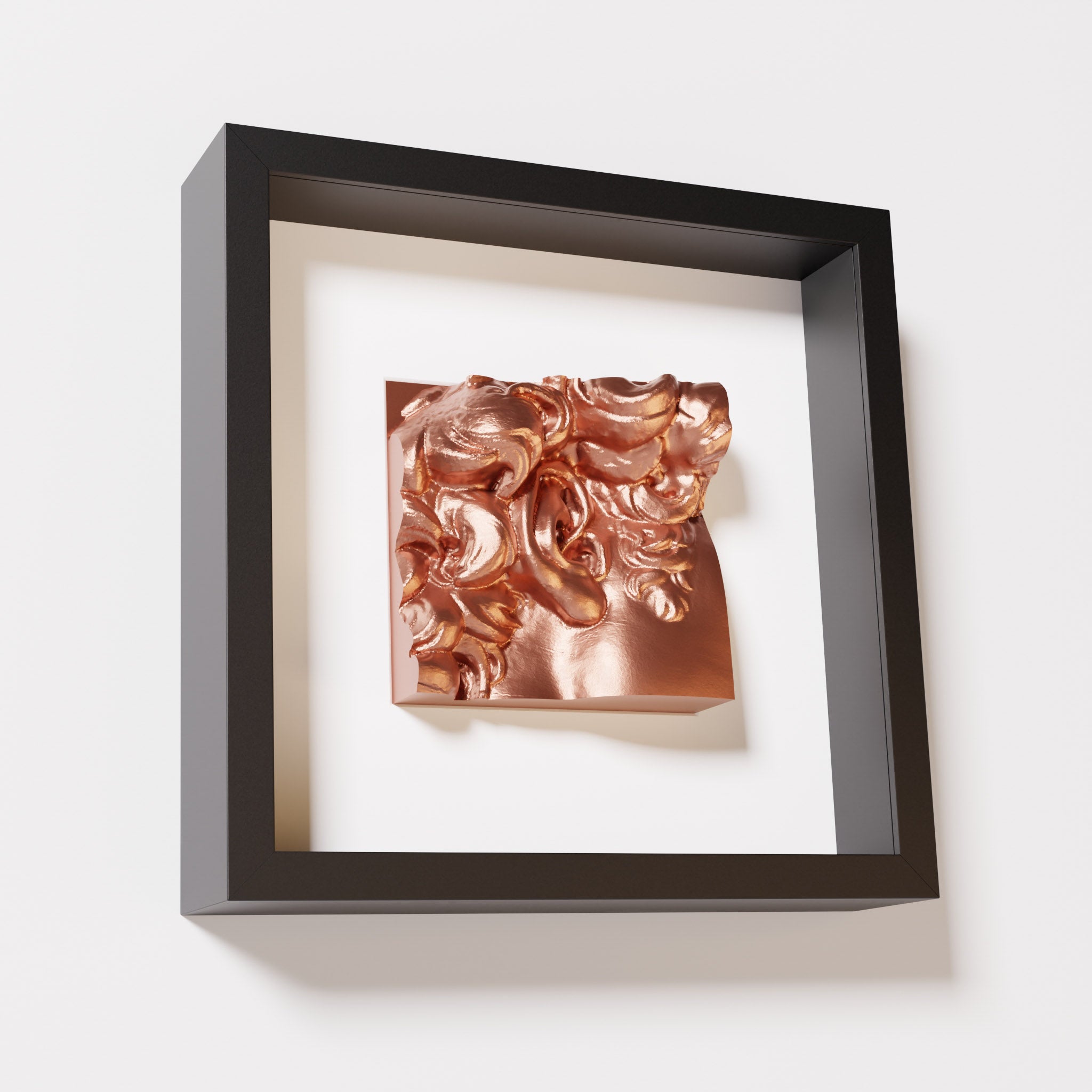 A close-up of a black shadowbox frame featuring a chrome copper sculpture of 'David's Ear.' The shiny copper tones and intricate details contrast beautifully with the black frame.