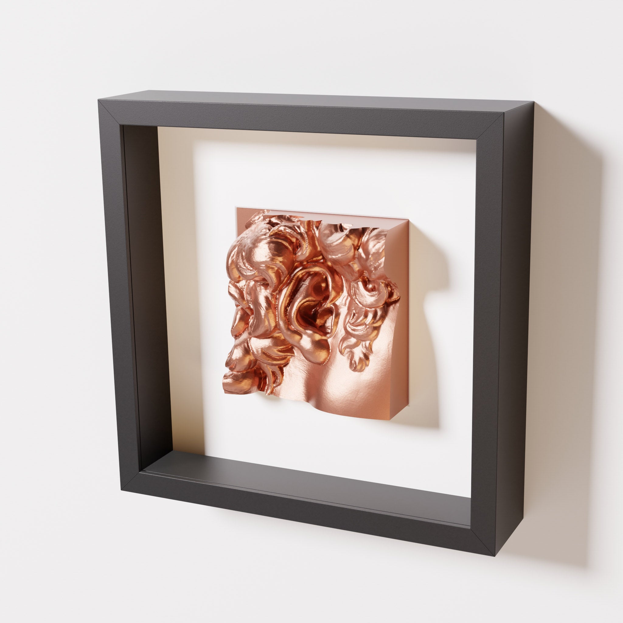 A close-up of a black shadowbox frame featuring a chrome copper sculpture of 'David's Ear.' The shiny copper tones and intricate details contrast beautifully with the black frame.