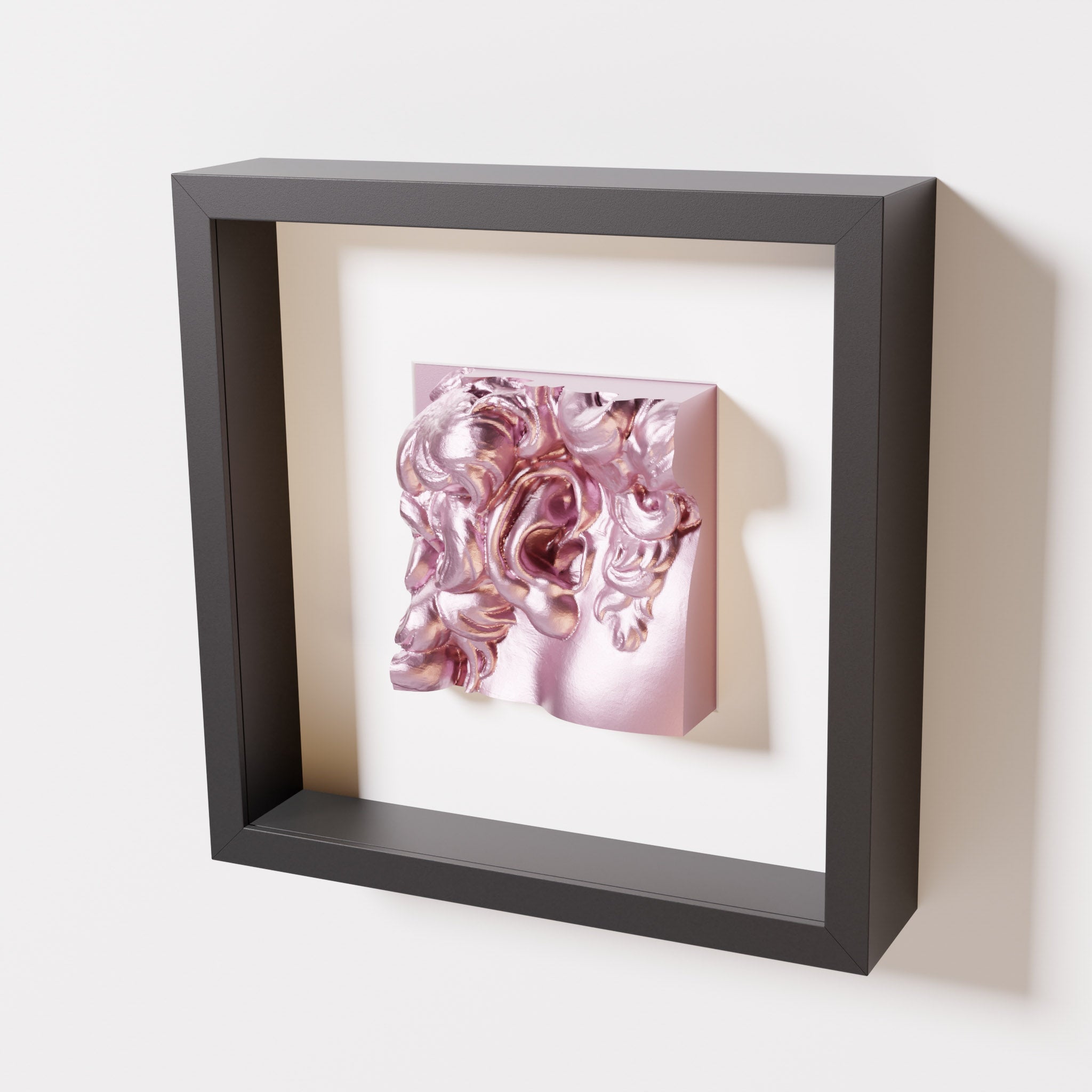 A close-up of a black shadowbox frame featuring a metallic rose sculpture of 'David's Ear.' The reflective pink tones and intricate details stand out against the black frame.