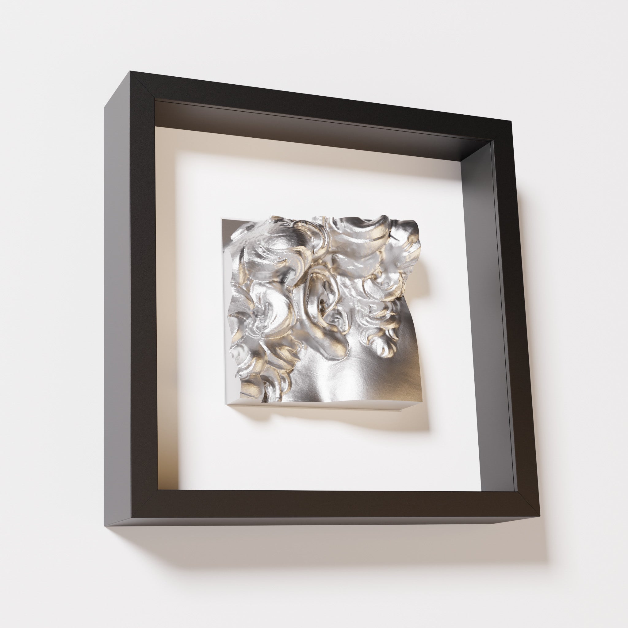 A close-up of a black shadowbox frame containing a chrome silver sculpture of 'David's Ear.' The shiny silver surface and intricate ear details contrast with the black frame.