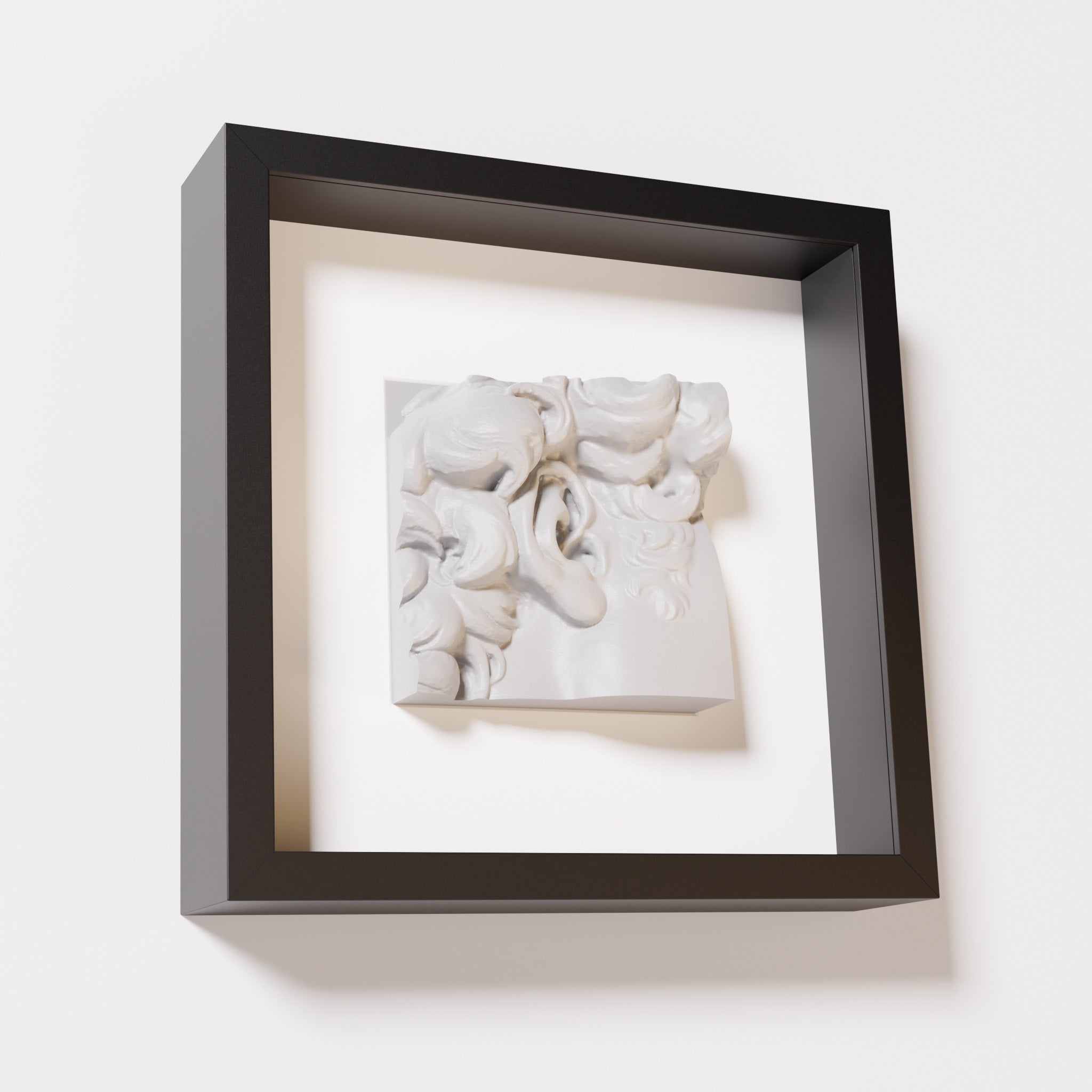 A close-up of a black shadowbox frame containing a marble white sculpture of 'David's Ear.' The detailed curls and ear contrast against the dark black frame.