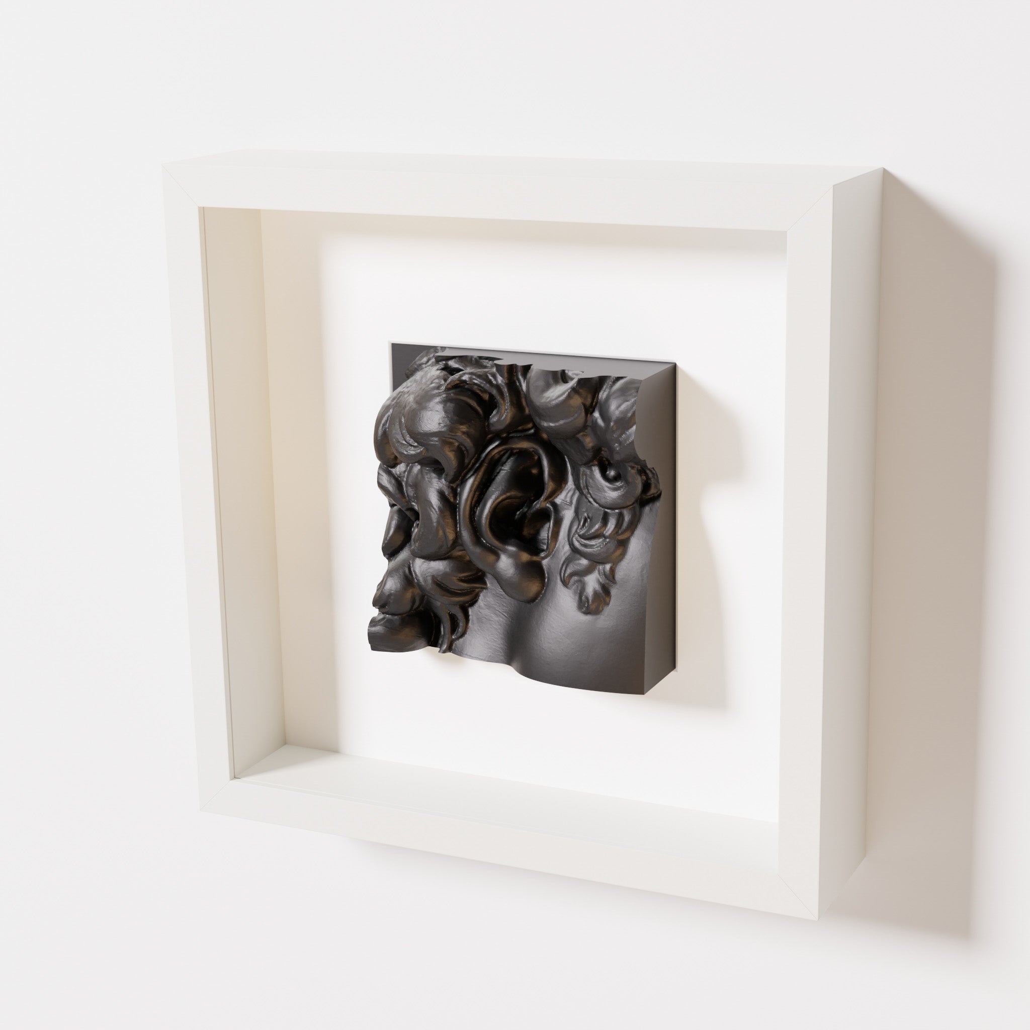 A close-up of a white shadowbox frame containing a matte black sculpture of 'David's Ear.' The artwork shows intricate curls and ear details, set against a minimalist white frame.