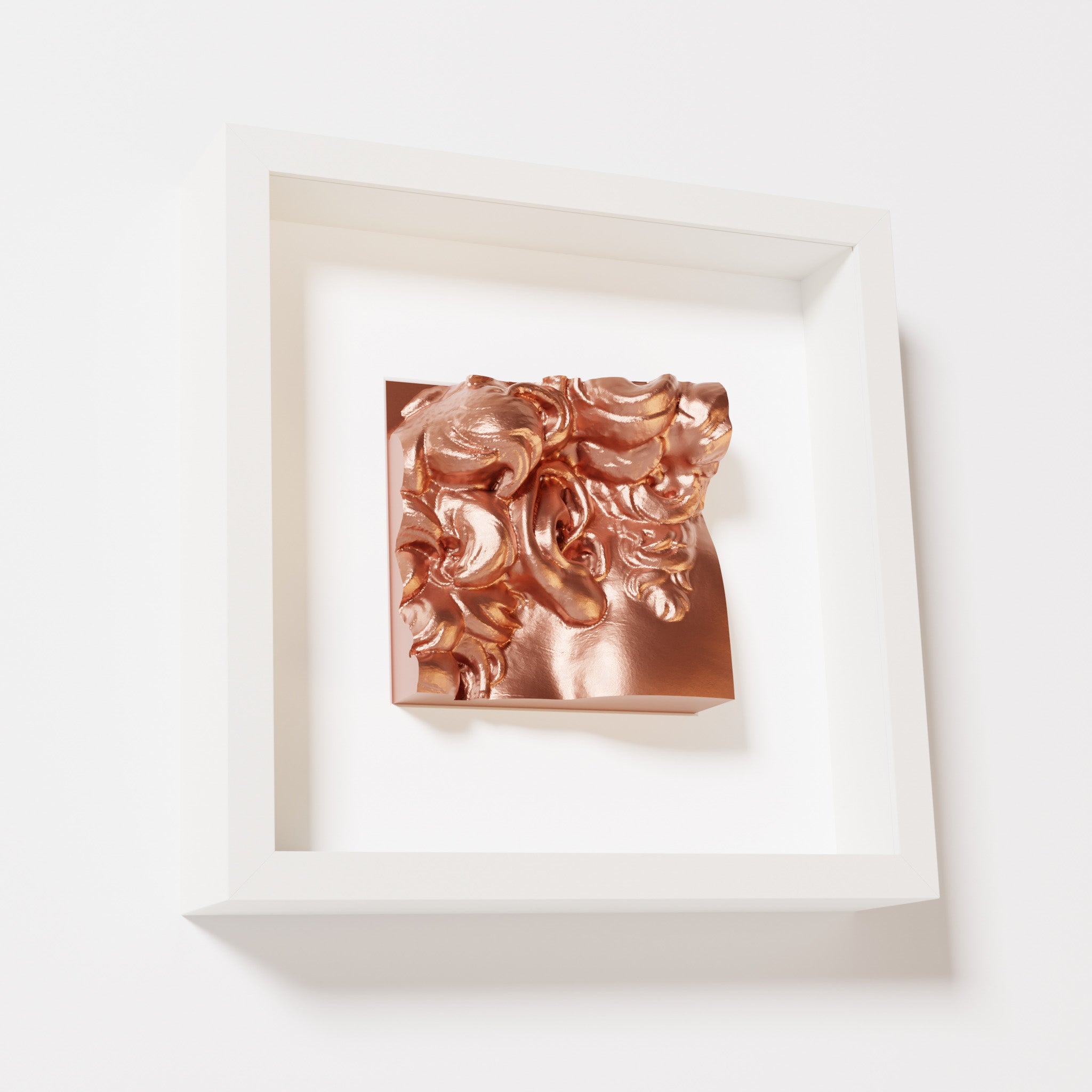 A close-up of a white shadowbox frame holding a chrome copper sculpture of 'David's Ear.' The warm, reflective copper finish emphasizes the detailed ear and curls.