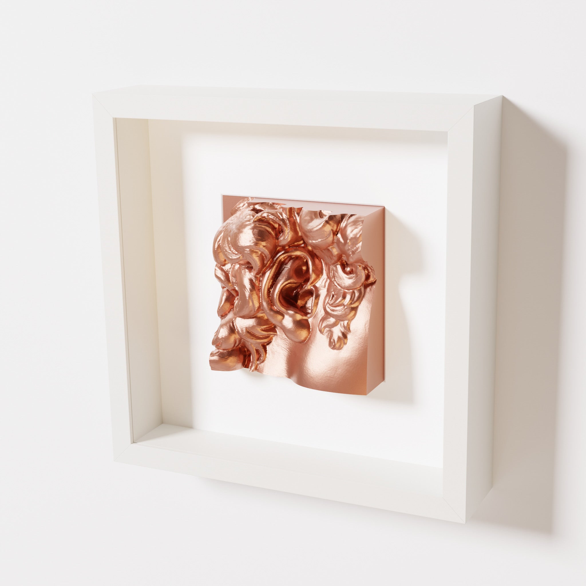 A close-up of a white shadowbox frame holding a chrome copper sculpture of 'David's Ear.' The warm, reflective copper finish emphasizes the detailed ear and curls.