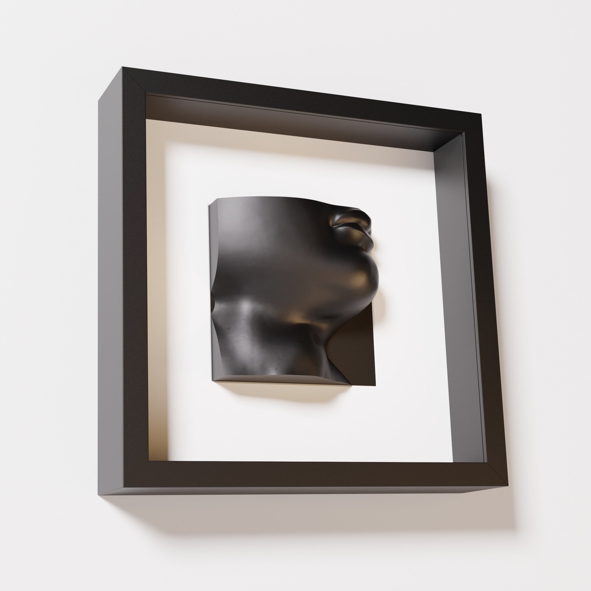 A close-up of a black shadowbox frame containing a matte black sculpture of 'David's Lip,' highlighting the detailed lips, chin, and surrounding textures of Michelangelo's David.