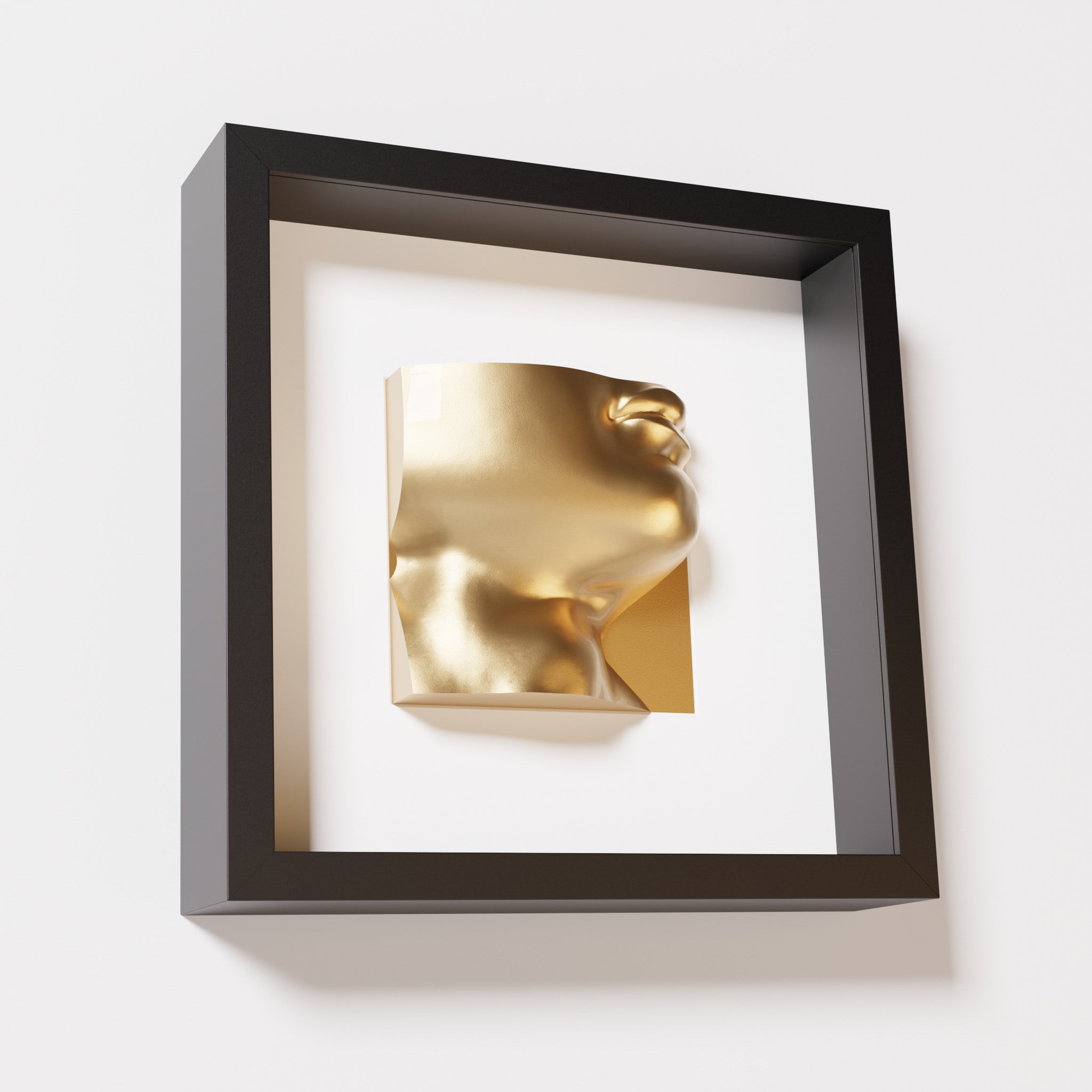 A close-up of a black shadowbox frame containing a chrome gold sculpture of 'David's Lip,' highlighting the detailed lips, chin, and reflective gold finish inspired by Michelangelo's David.