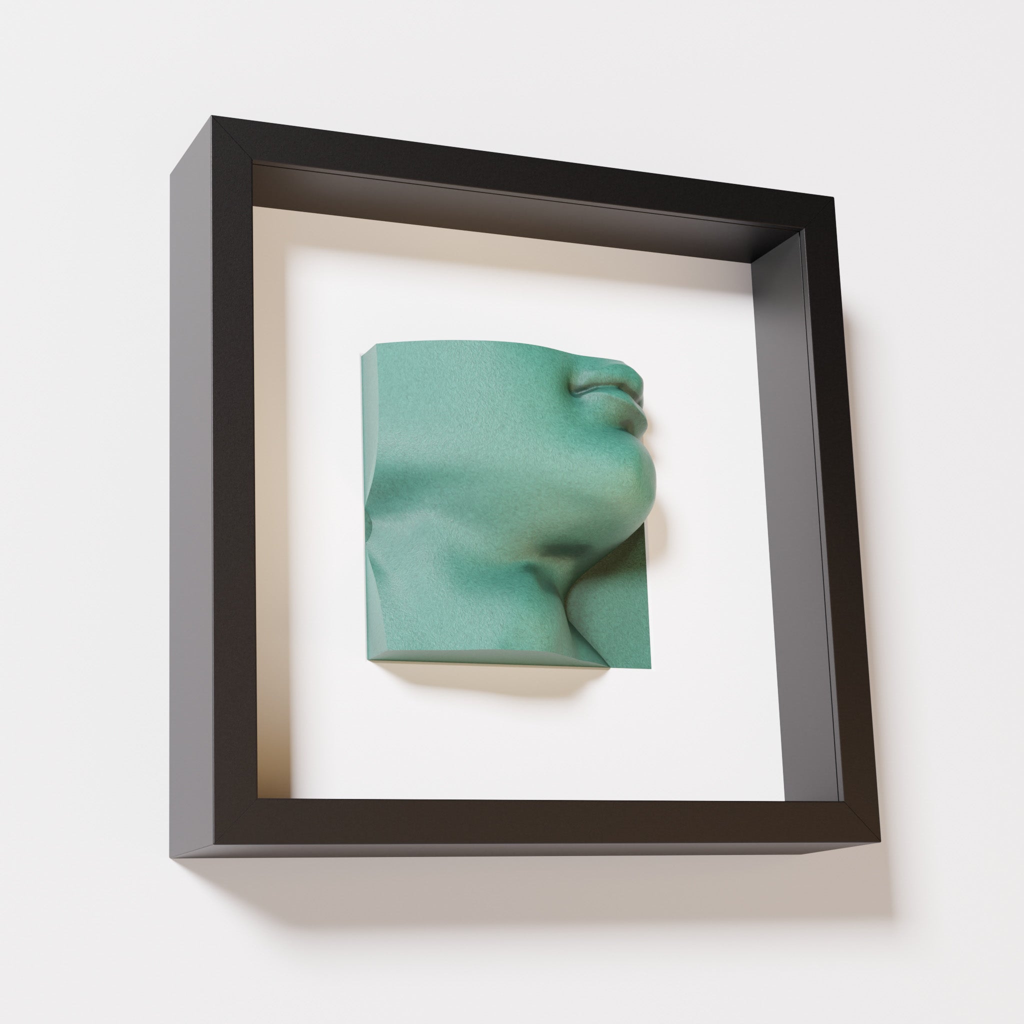 A close-up of a black shadowbox frame containing an old patina sculpture of 'David's Lip,' highlighting the detailed lips, chin, and textured green finish inspired by Michelangelo's David.