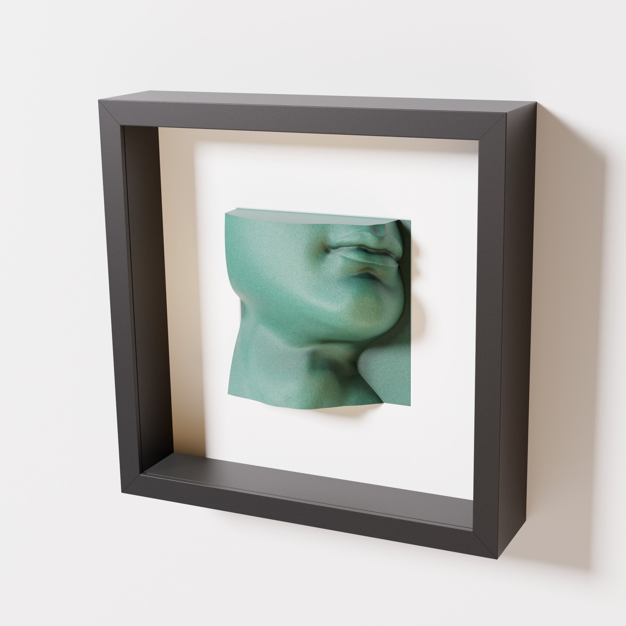 A close-up of a black shadowbox frame containing an old patina sculpture of 'David's Lip,' highlighting the detailed lips, chin, and textured green finish inspired by Michelangelo's David.