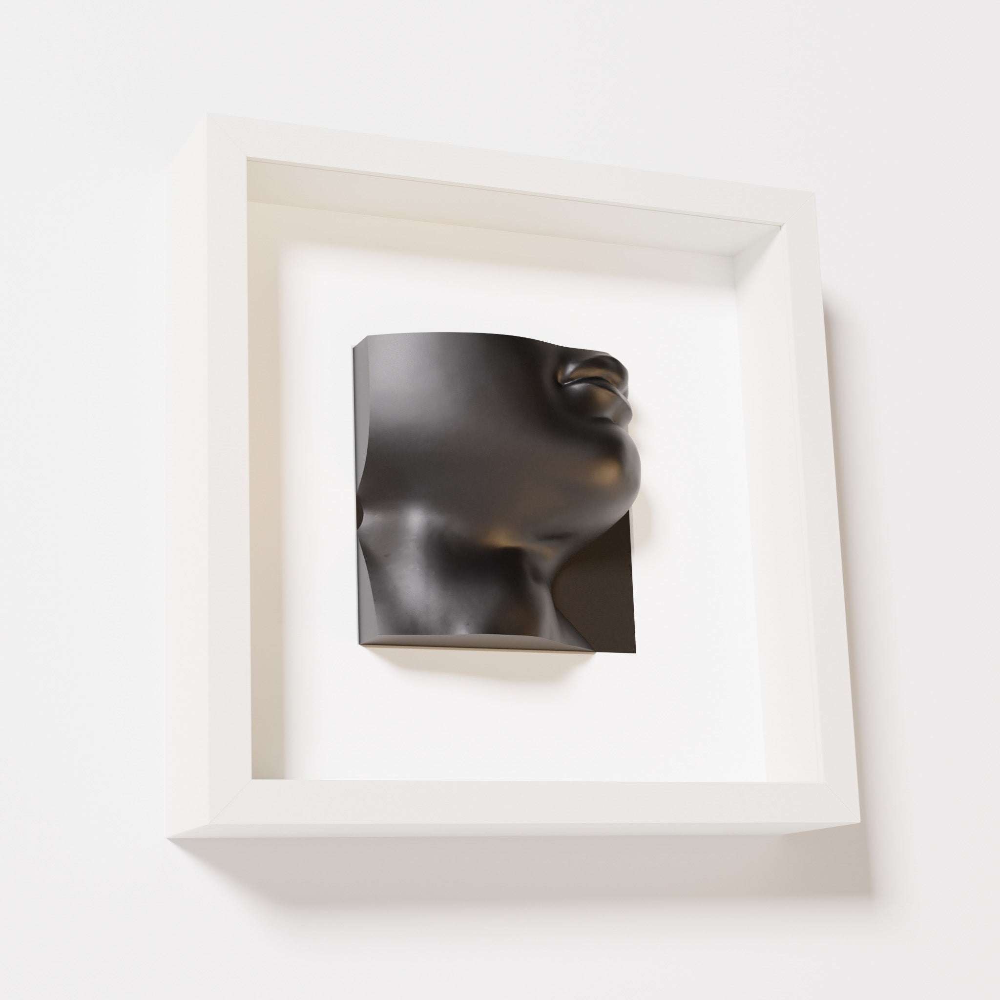 A close-up of a white shadowbox frame containing a matte black sculpture of 'David's Lip,' highlighting the detailed lips, chin, and surrounding textures of Michelangelo's David.