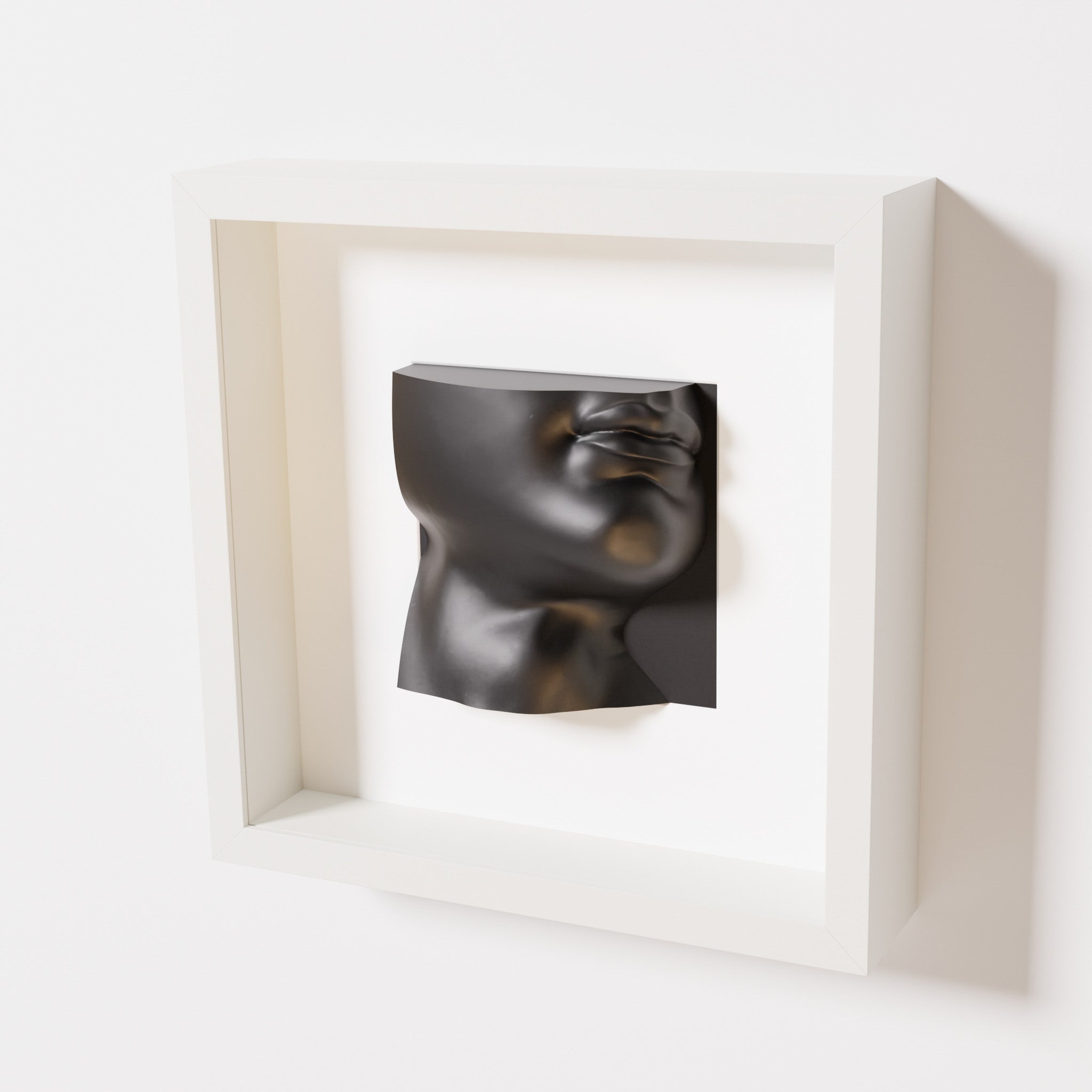 A close-up of a white shadowbox frame containing a matte black sculpture of 'David's Lip,' highlighting the detailed lips, chin, and surrounding textures of Michelangelo's David.