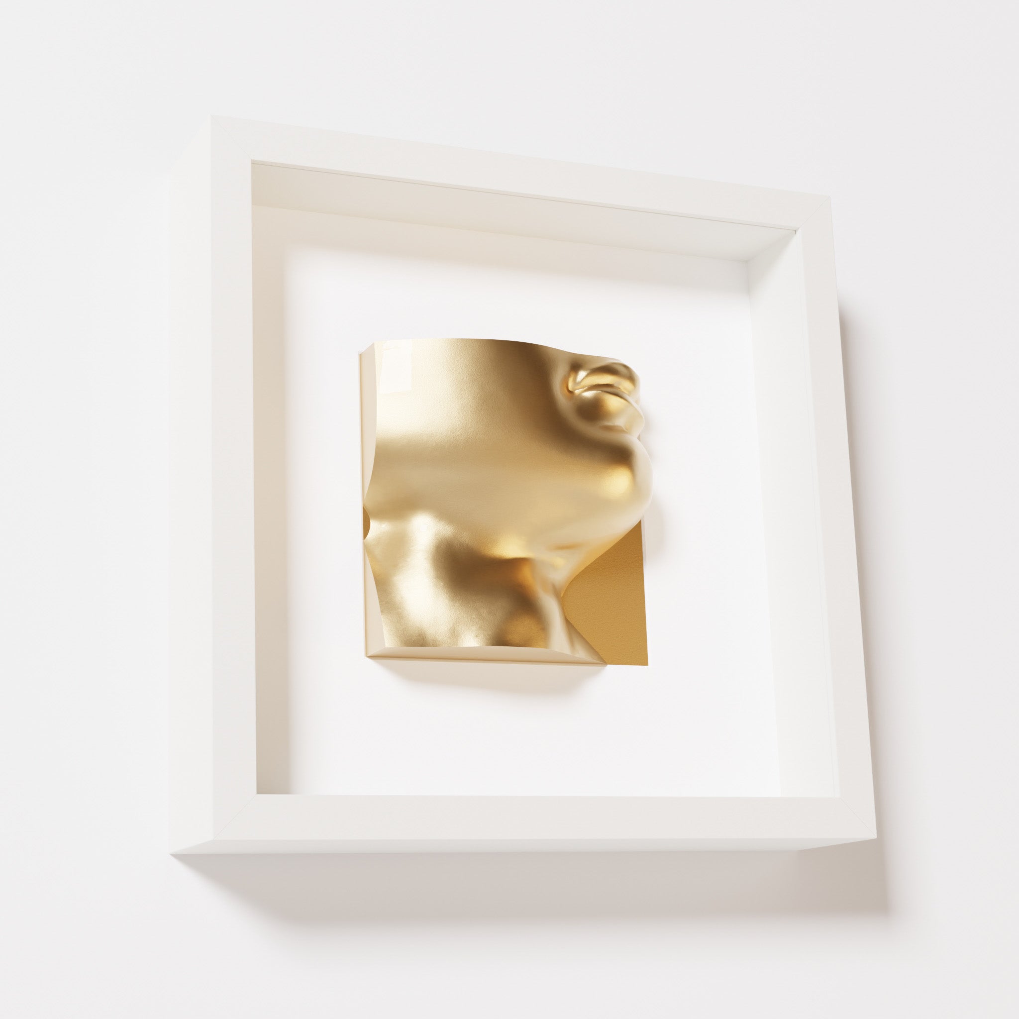 A close-up of a white shadowbox frame containing a chrome gold sculpture of 'David's Lip,' highlighting the detailed lips, chin, and reflective gold finish inspired by Michelangelo's David.