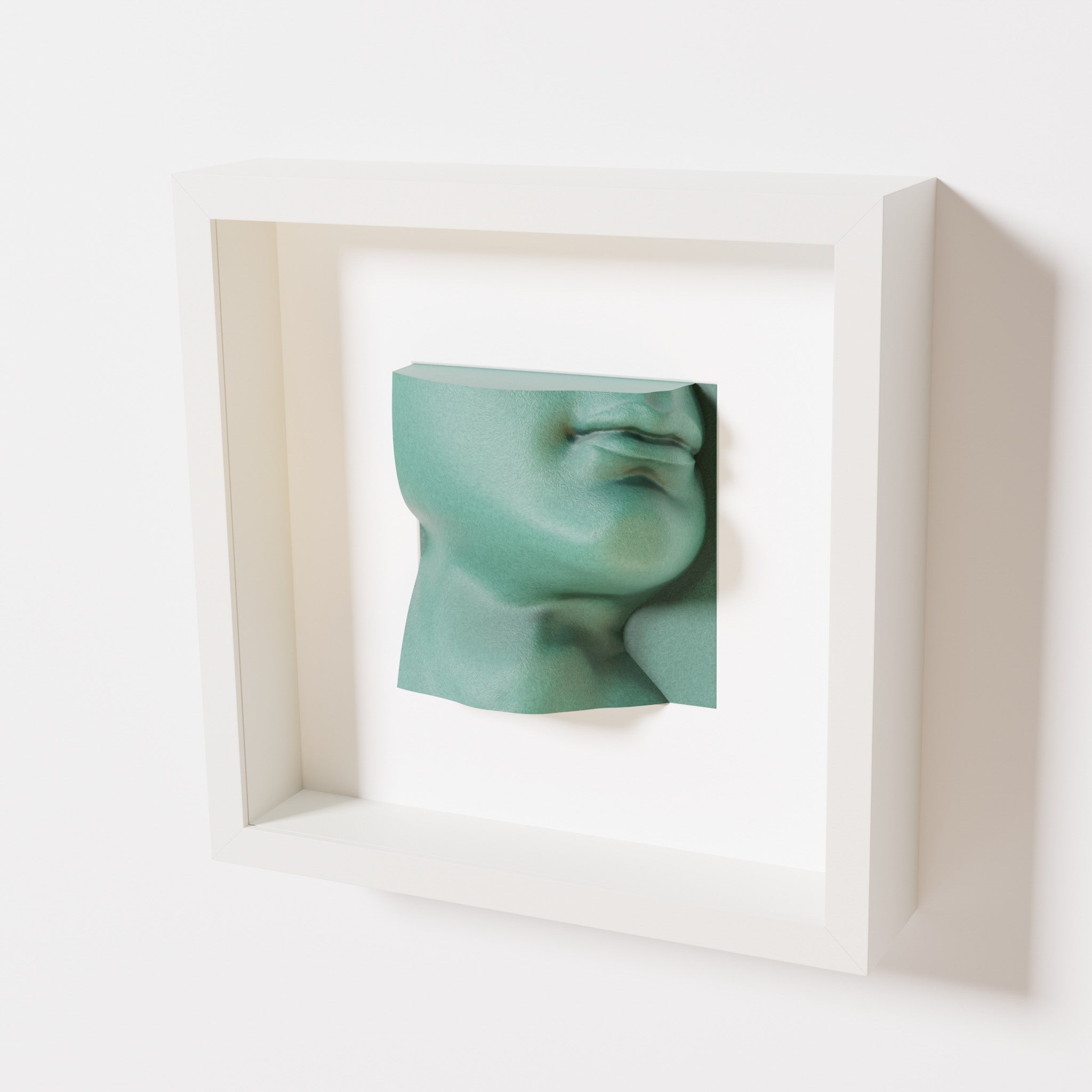 A close-up of a white shadowbox frame containing an old patina sculpture of 'David's Lip,' highlighting the detailed lips, chin, and textured green finish inspired by Michelangelo's David.