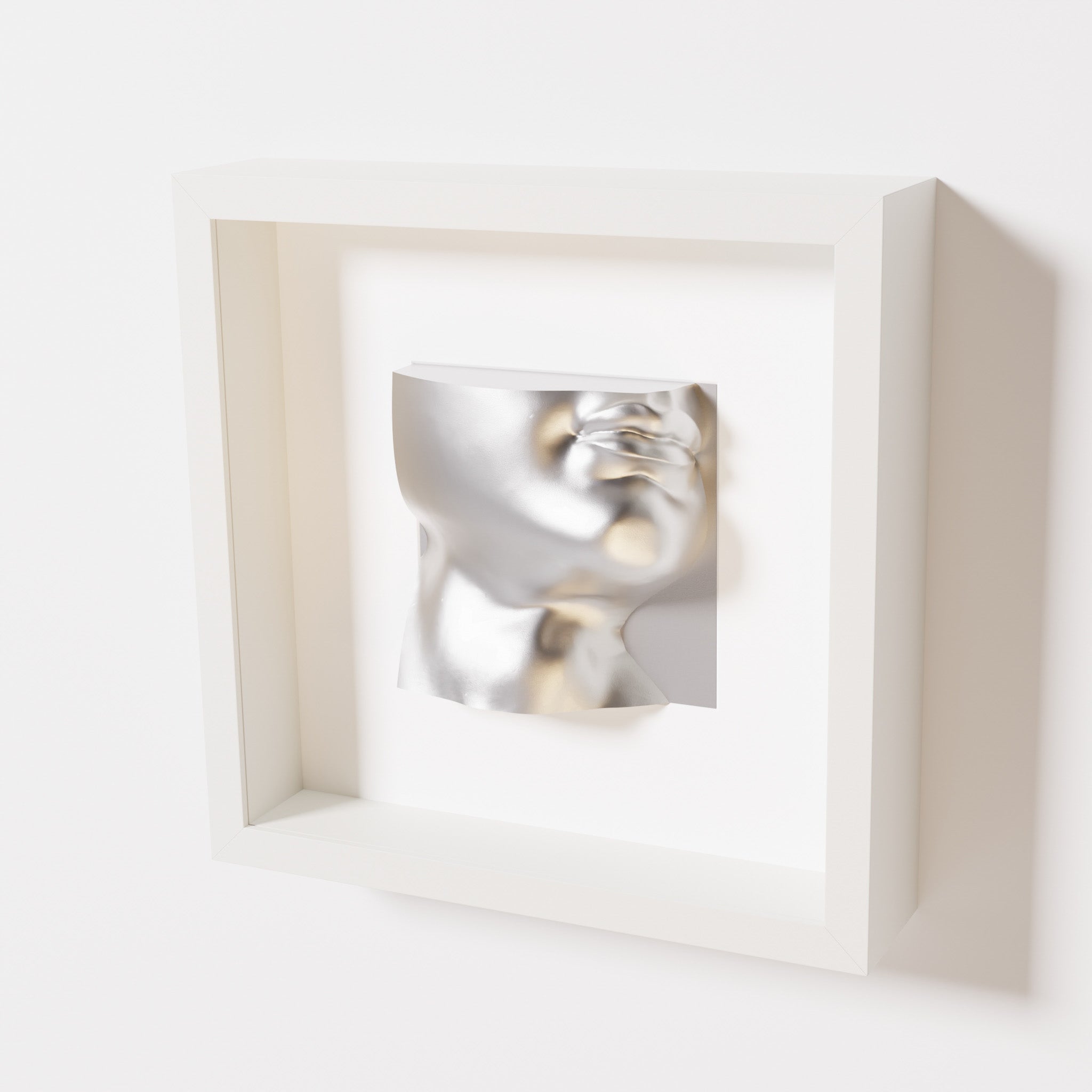 A close-up of a white shadowbox frame containing a chrome silver sculpture of 'David's Lip,' highlighting the detailed lips, chin, and reflective silver finish inspired by Michelangelo's David.