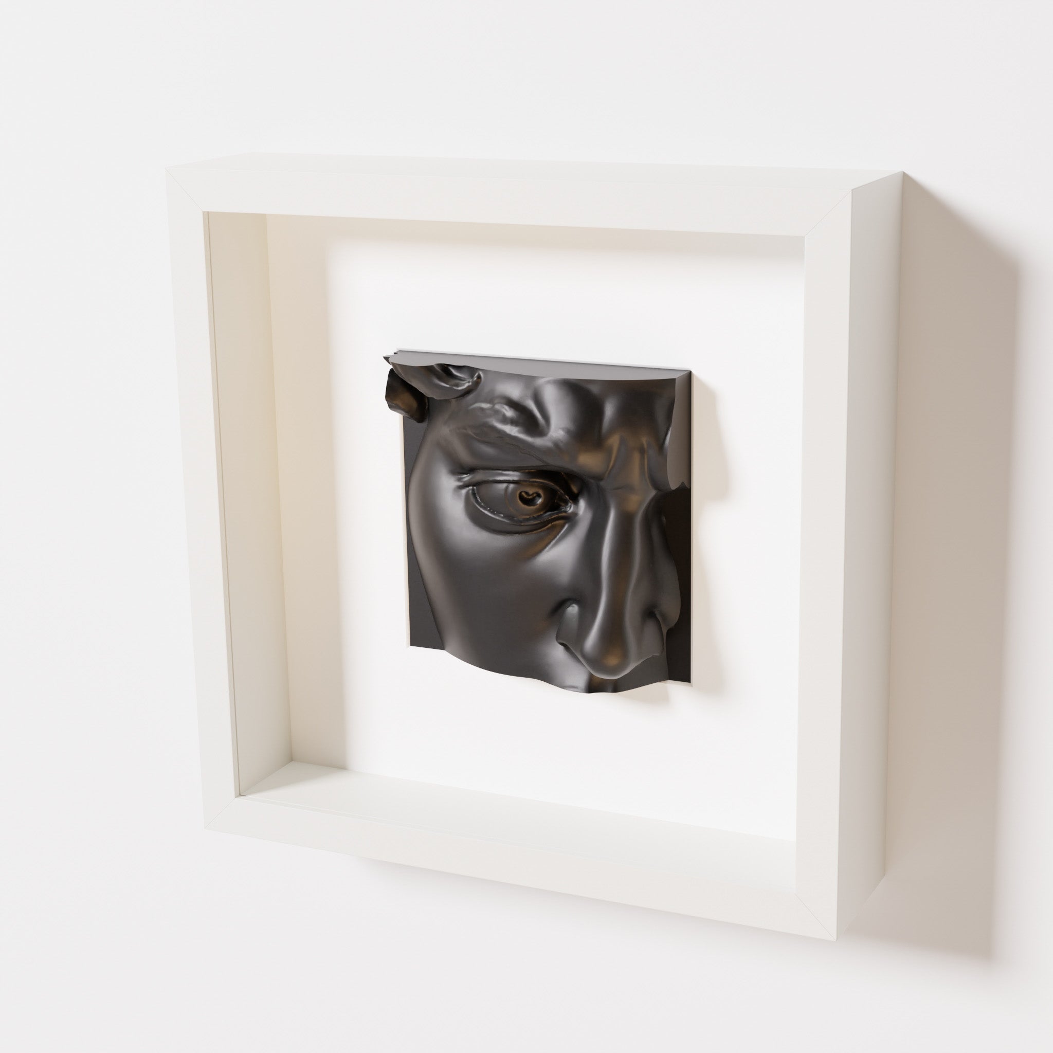 A close-up of a white shadowbox frame containing a matte black sculpture of 'David's Eye,' highlighting the intricate details of the eye, brow, and surrounding textures.