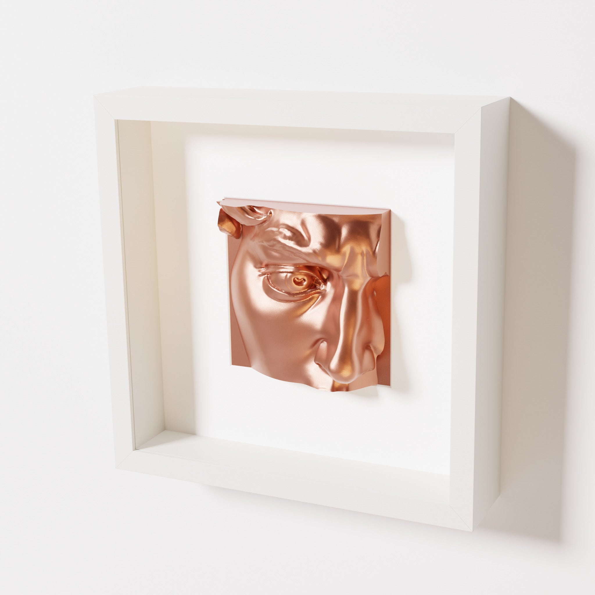 A close-up of a white shadowbox frame containing a chrome copper sculpture of 'David's Eye,' highlighting the intricate details of the eye, brow, and surrounding textures.