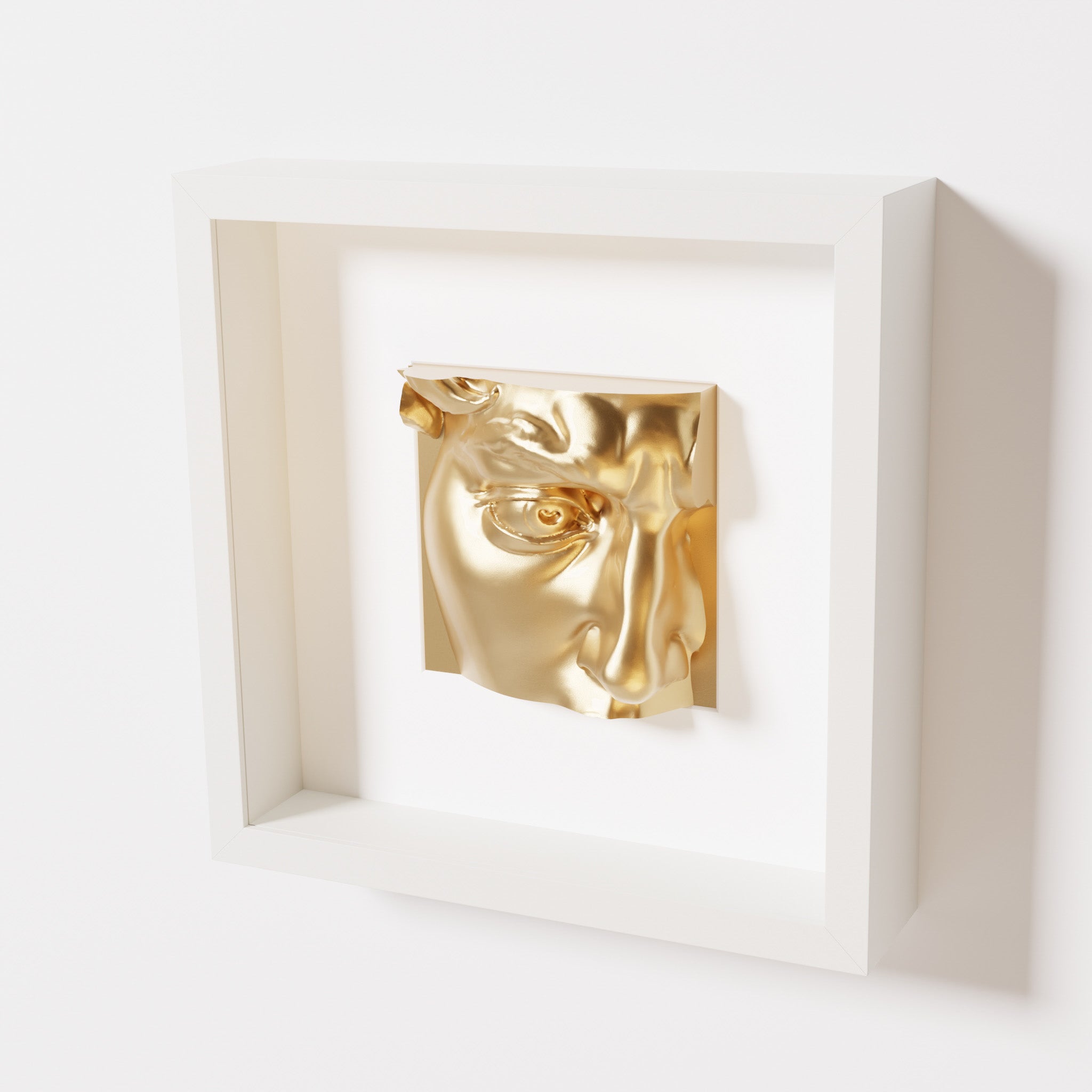 A close-up of a white shadowbox frame containing a chrome gold sculpture of 'David's Eye,' highlighting the intricate details of the eye, brow, and surrounding textures.