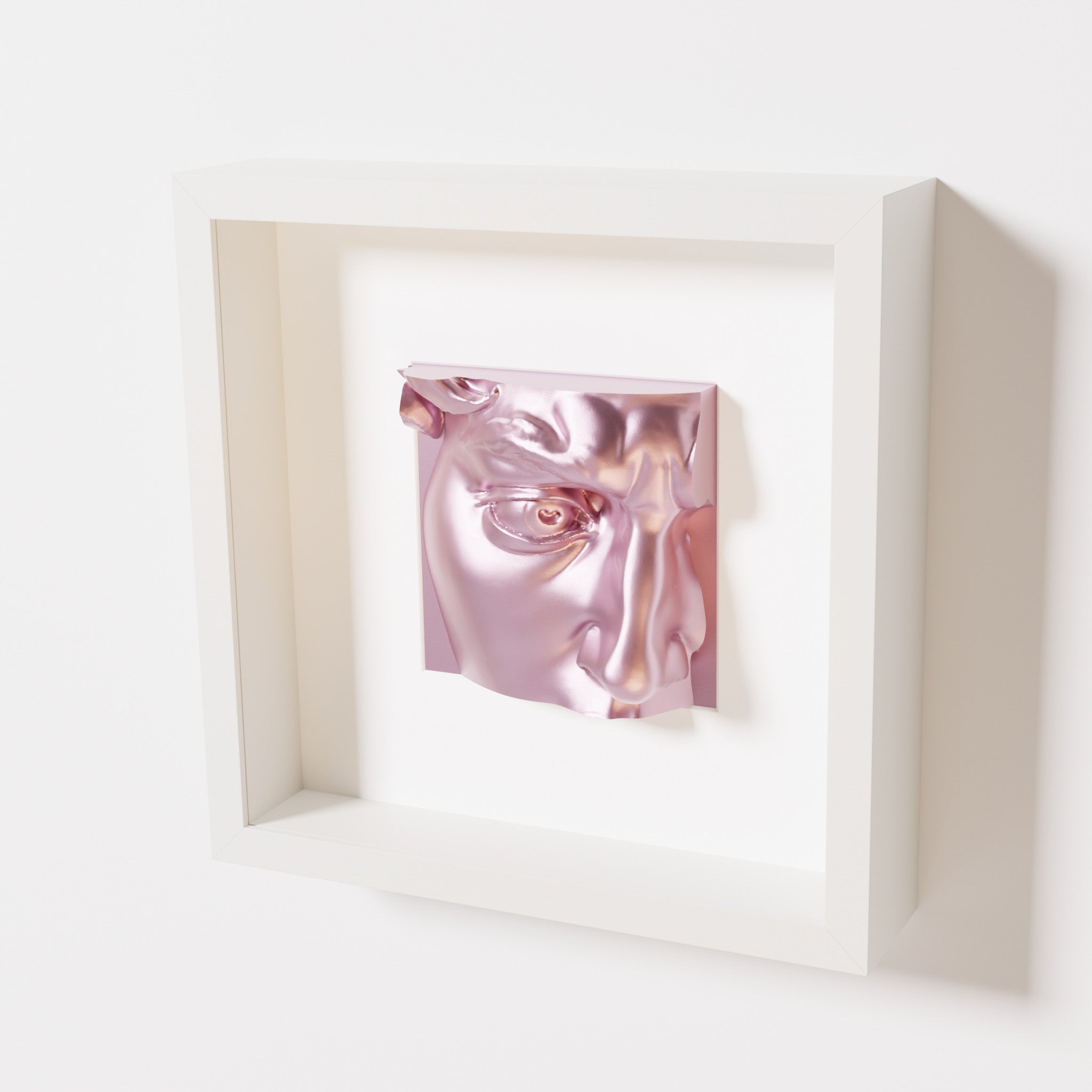 A close-up of a white shadowbox frame containing a metallic rose sculpture of 'David's Eye,' highlighting the intricate details of the eye, brow, and surrounding textures.