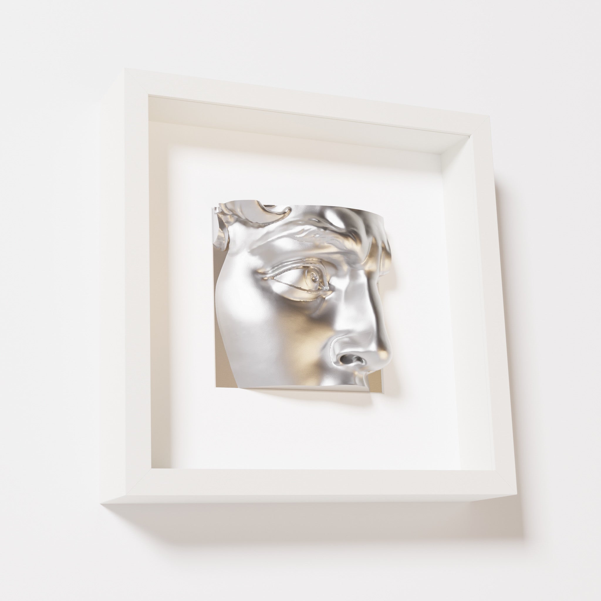 A close-up of a white shadowbox frame containing a chrome silver sculpture of 'David's Eye,' highlighting the intricate details of the eye, brow, and surrounding textures.