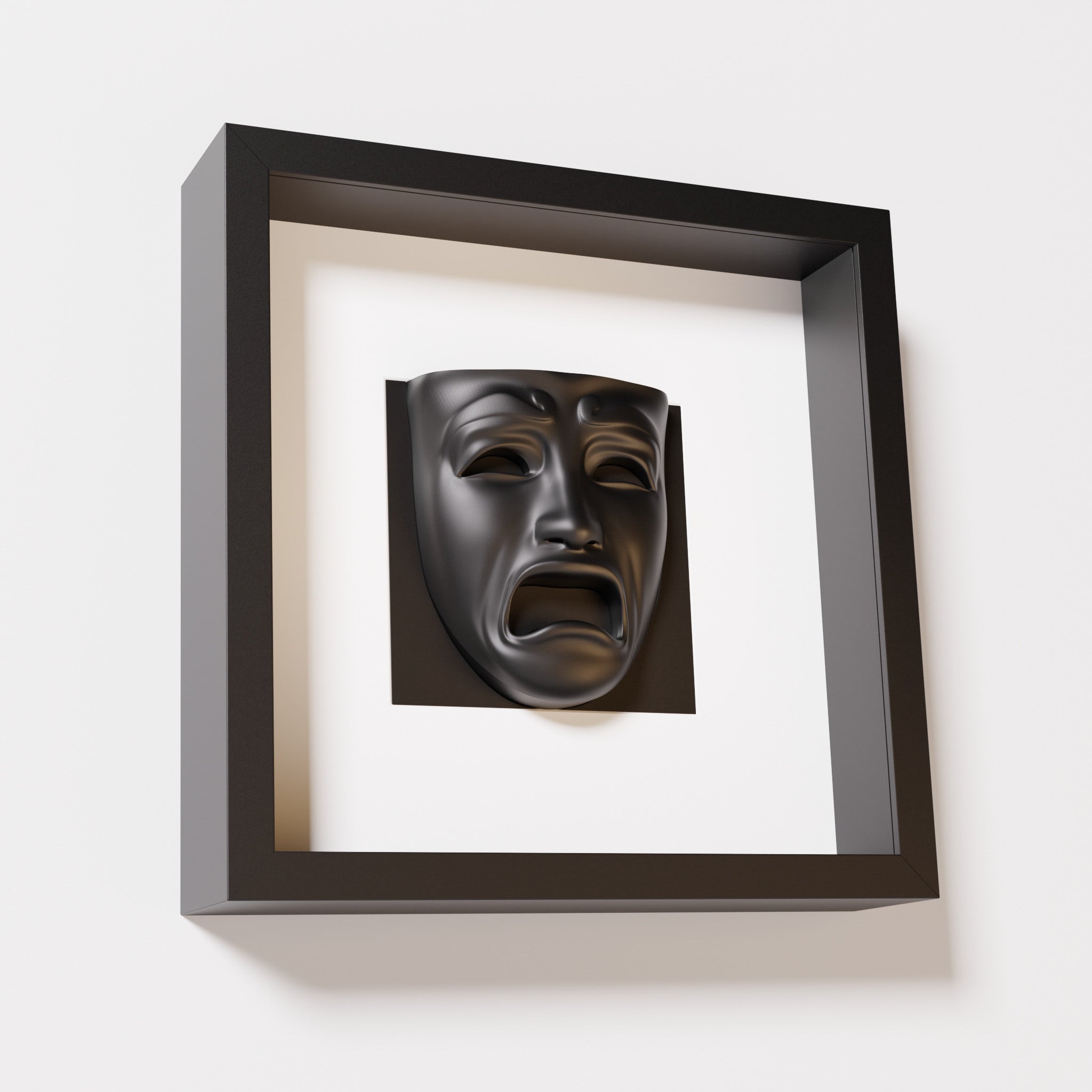 A close-up of a black shadowbox frame containing a matte black sculpture of 'Despair,' showcasing the expressive mask with furrowed brows, hollow eyes, and an open mouth.