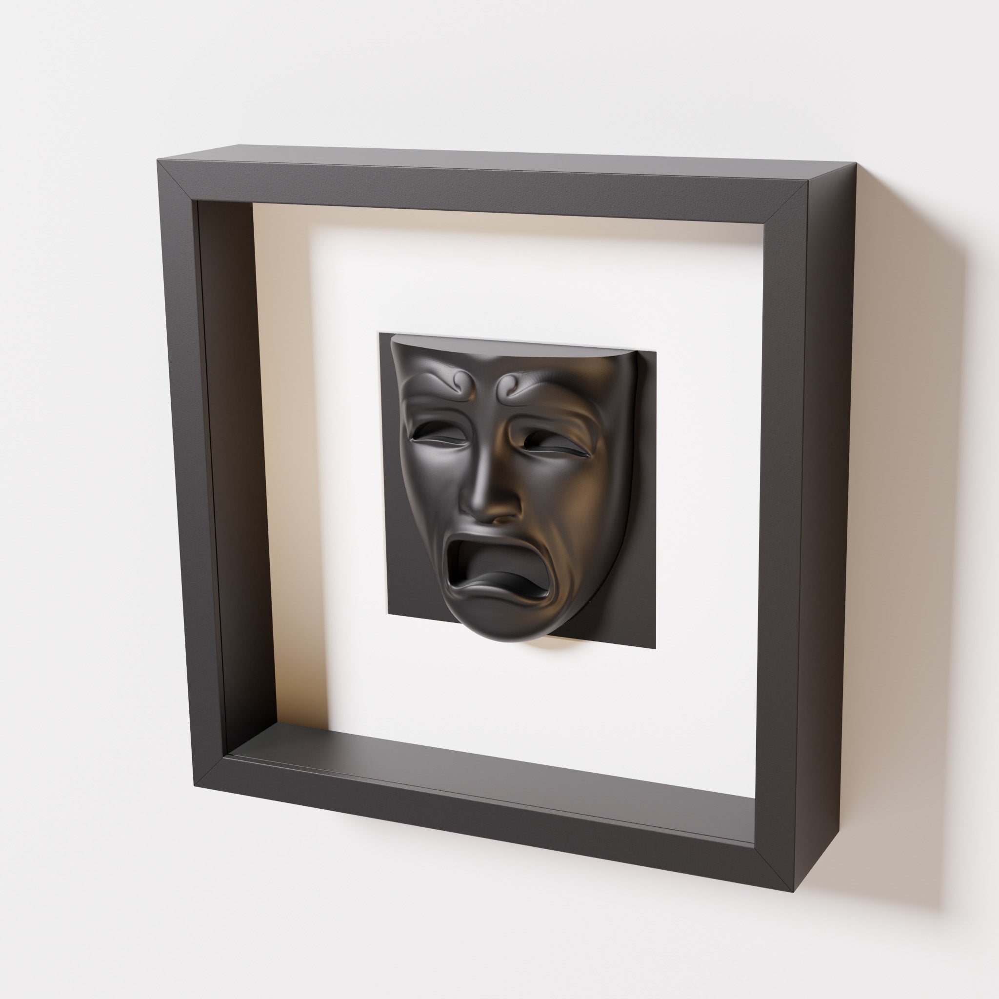 A close-up of a black shadowbox frame containing a matte black sculpture of 'Despair,' showcasing the expressive mask with furrowed brows, hollow eyes, and an open mouth.