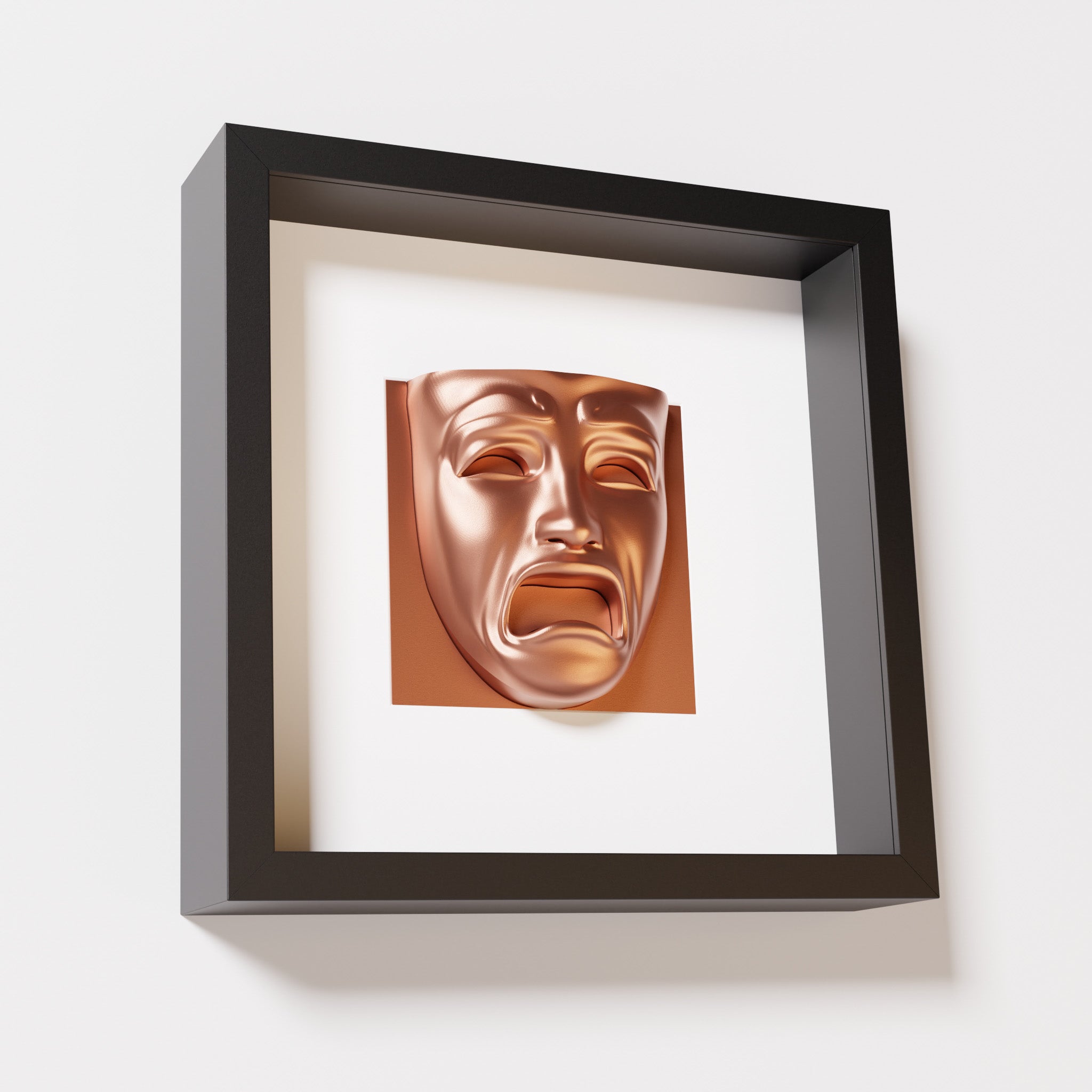 A close-up of a black shadowbox frame containing a chrome copper sculpture of 'Despair,' showcasing the expressive mask with furrowed brows, hollow eyes, and an open mouth.