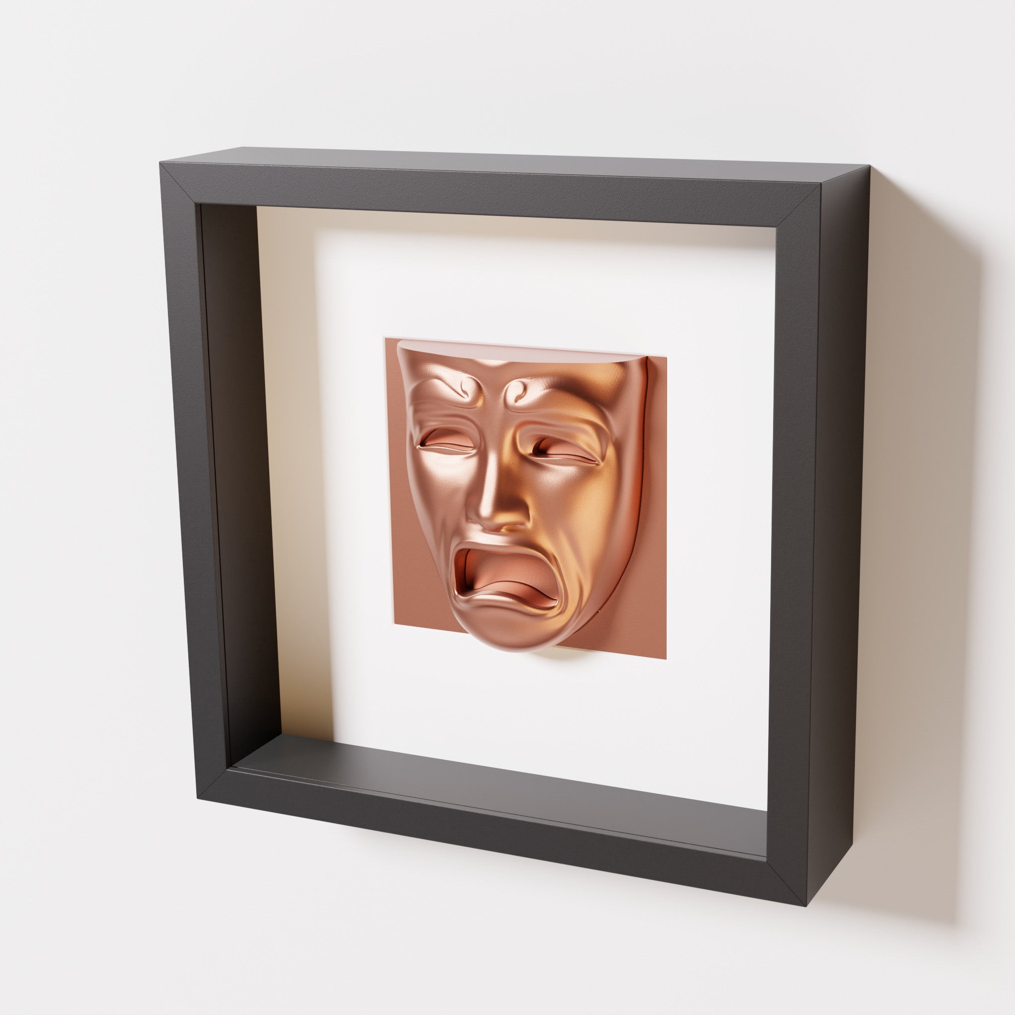 A close-up of a black shadowbox frame containing a chrome copper sculpture of 'Despair,' showcasing the expressive mask with furrowed brows, hollow eyes, and an open mouth.