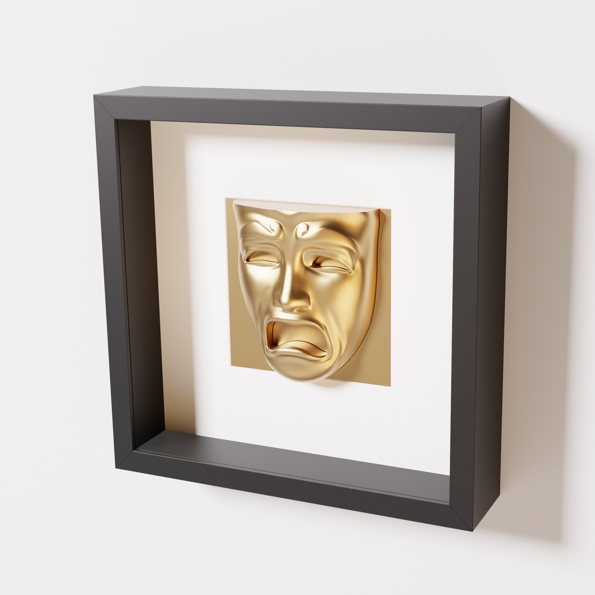 A close-up of a black shadowbox frame containing a chrome gold sculpture of 'Despair,' showcasing the expressive mask with furrowed brows, hollow eyes, and an open mouth.