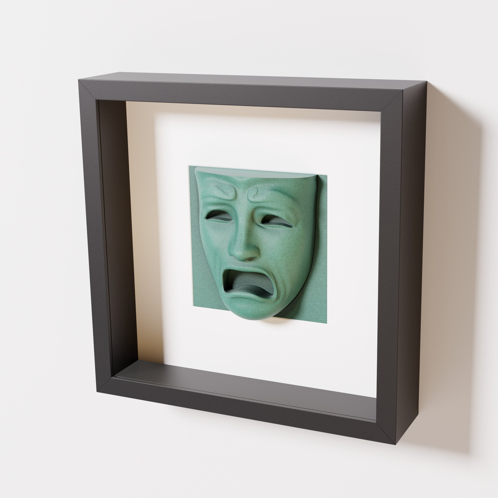 A close-up of a black shadowbox frame containing an old patina sculpture of 'Despair,' showcasing the expressive mask with furrowed brows, hollow eyes, and an open mouth.