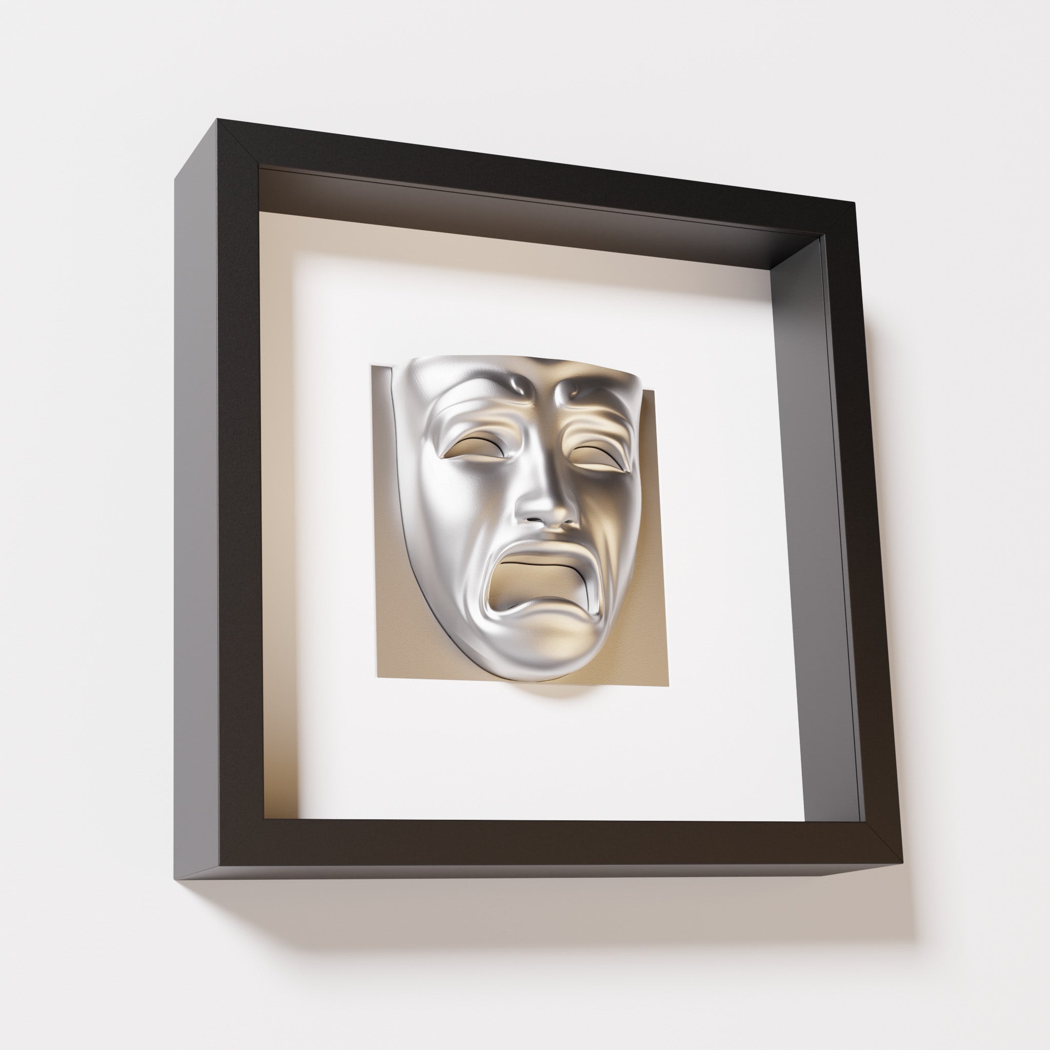 A close-up of a black shadowbox frame containing a chrome silver sculpture of 'Despair,' showcasing the expressive mask with furrowed brows, hollow eyes, and an open mouth.