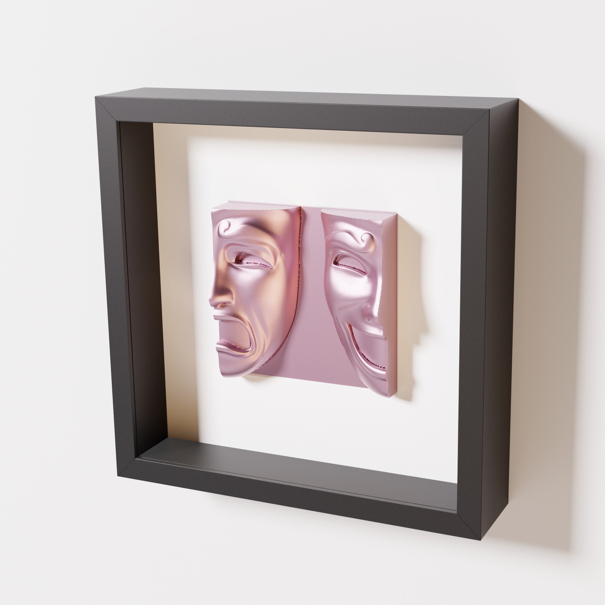 A close-up of a black shadowbox frame containing a metallic rose sculpture of 'Despair & Joy,' showcasing two expressive masks side by side: one with a sorrowful expression and the other with a joyful smile.