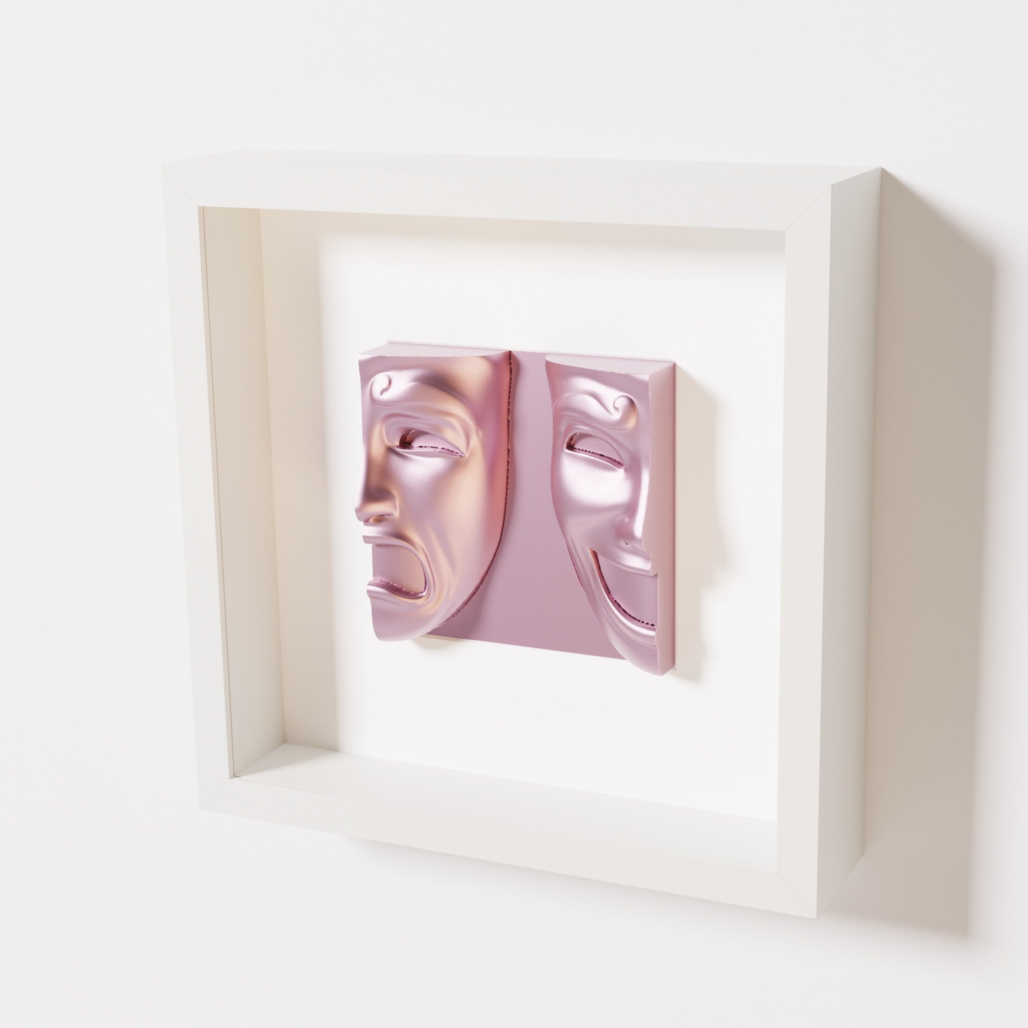 A close-up of a white shadowbox frame containing a metallic rose sculpture of 'Despair & Joy,' showcasing two expressive masks side by side: one with a sorrowful expression and the other with a joyful smile.