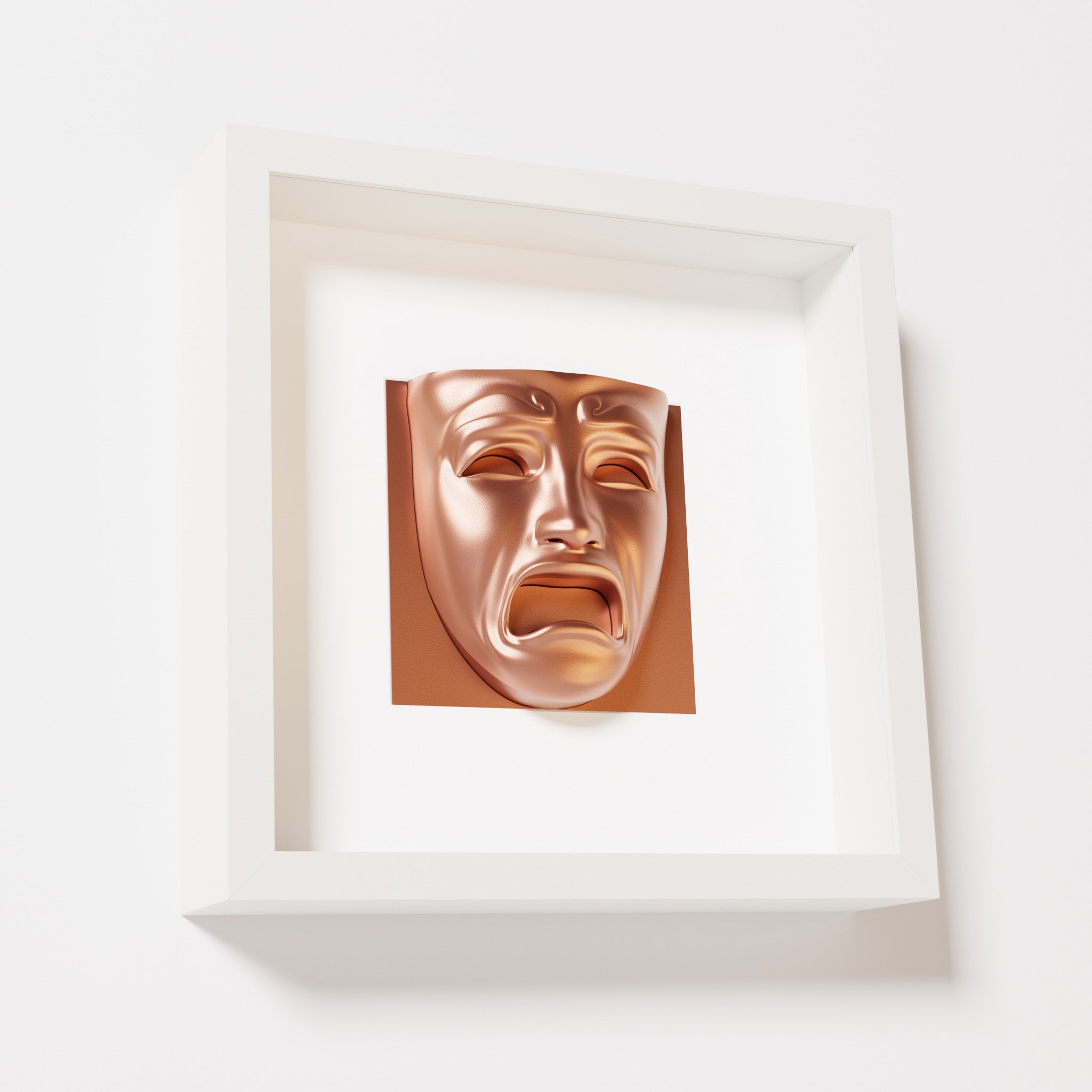 A close-up of a white shadowbox frame containing a chrome copper sculpture of 'Despair,' showcasing the expressive mask with furrowed brows, hollow eyes, and an open mouth.