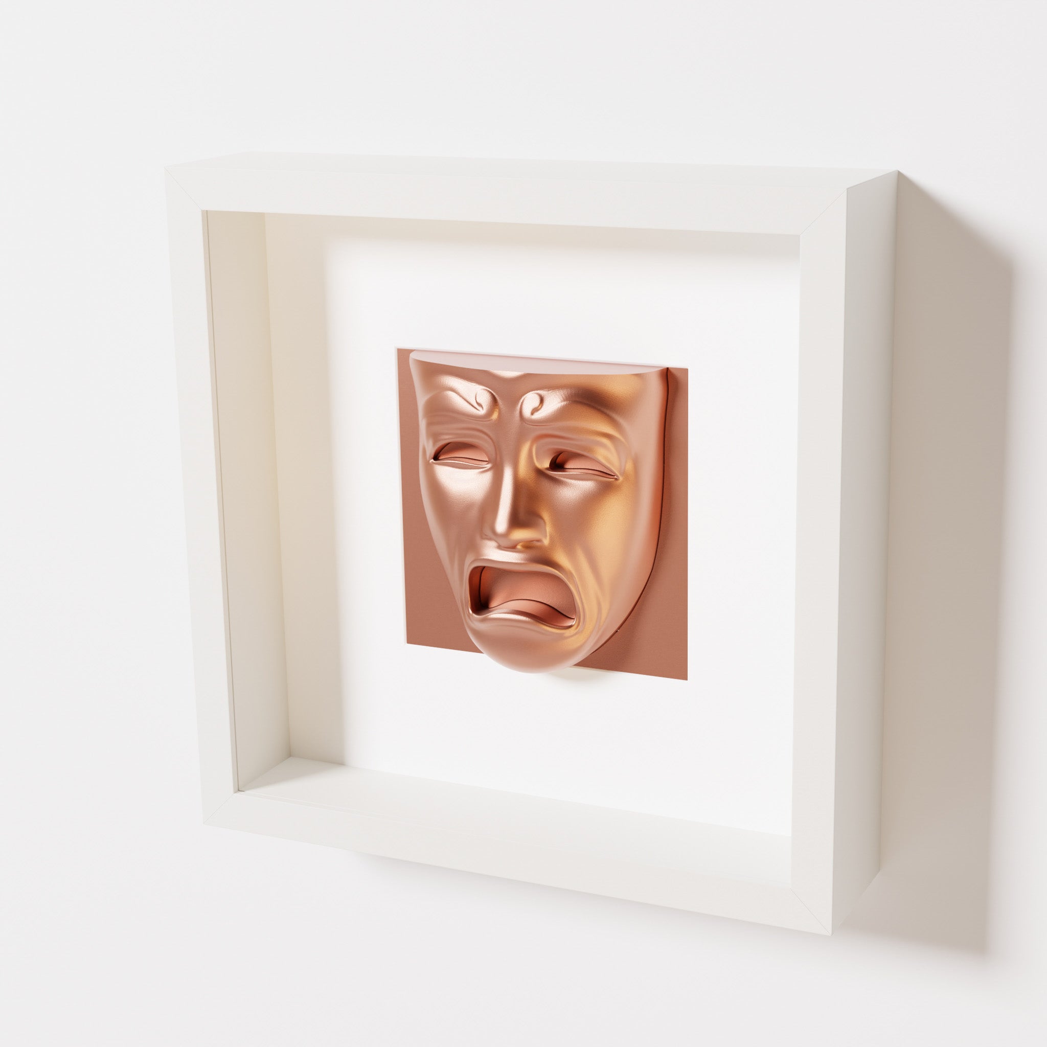 A close-up of a white shadowbox frame containing a chrome copper sculpture of 'Despair,' showcasing the expressive mask with furrowed brows, hollow eyes, and an open mouth.