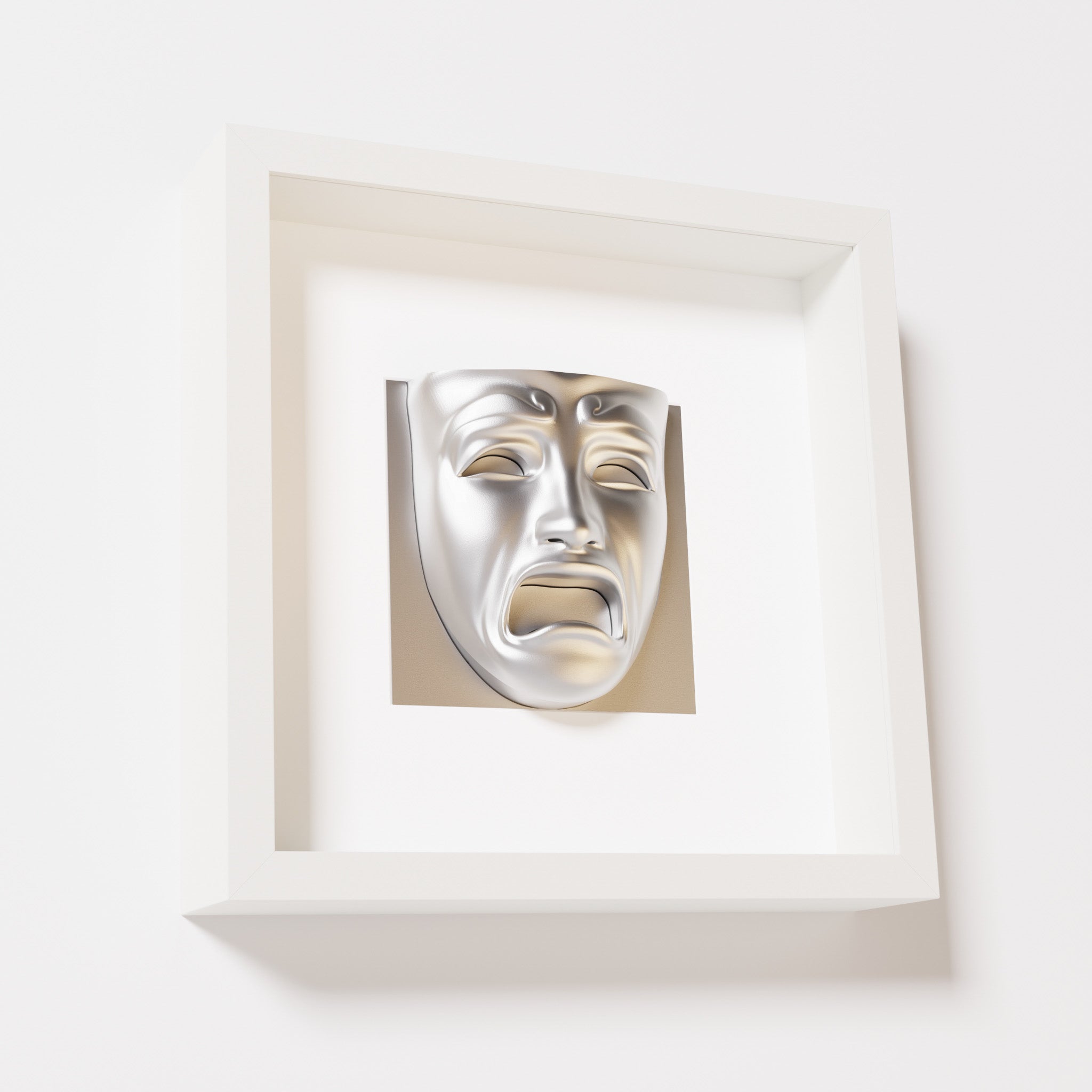 A close-up of a white shadowbox frame containing a chrome silver sculpture of 'Despair,' showcasing the expressive mask with furrowed brows, hollow eyes, and an open mouth.