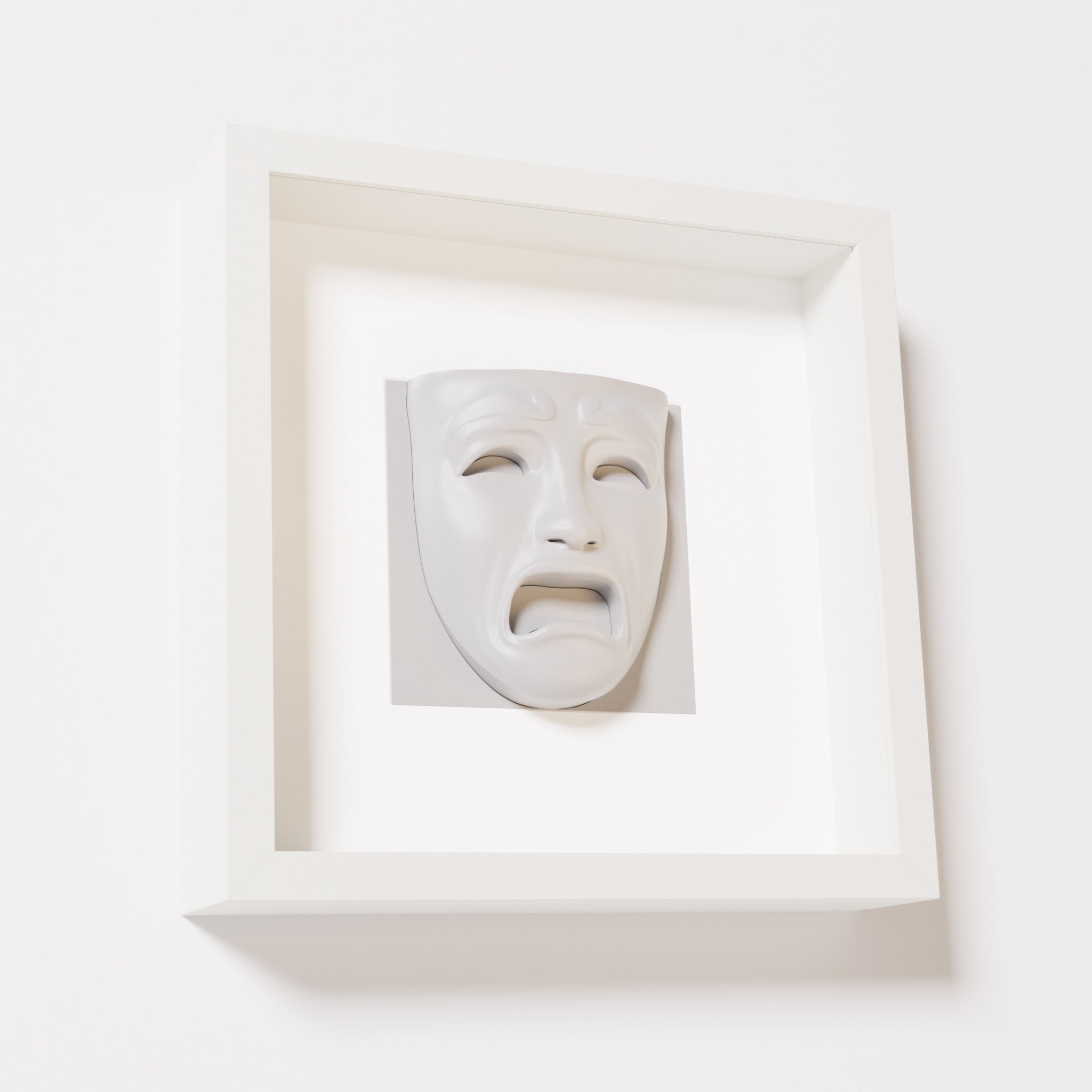 A close-up of a white shadowbox frame containing a marble white sculpture of 'Despair,' showcasing the expressive mask with furrowed brows, hollow eyes, and an open mouth.