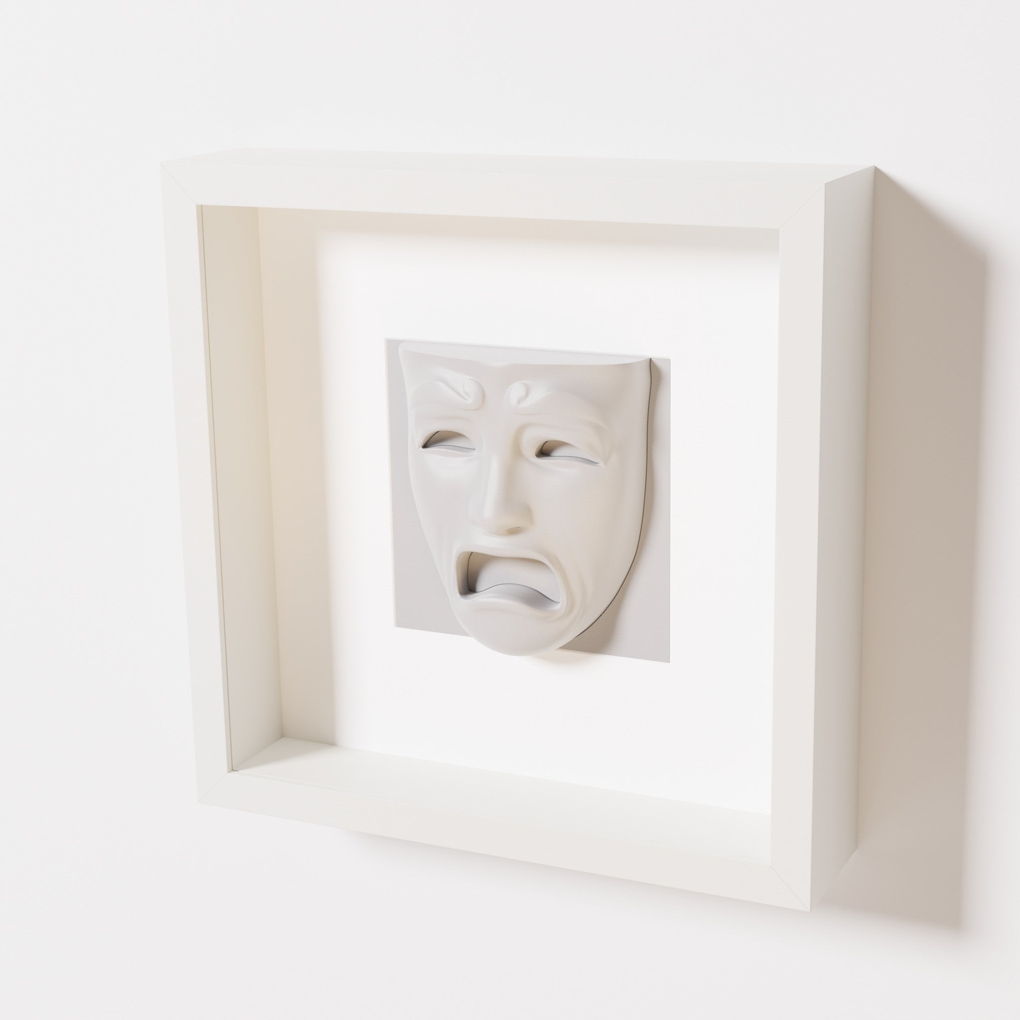 A close-up of a white shadowbox frame containing a marble white sculpture of 'Despair,' showcasing the expressive mask with furrowed brows, hollow eyes, and an open mouth.