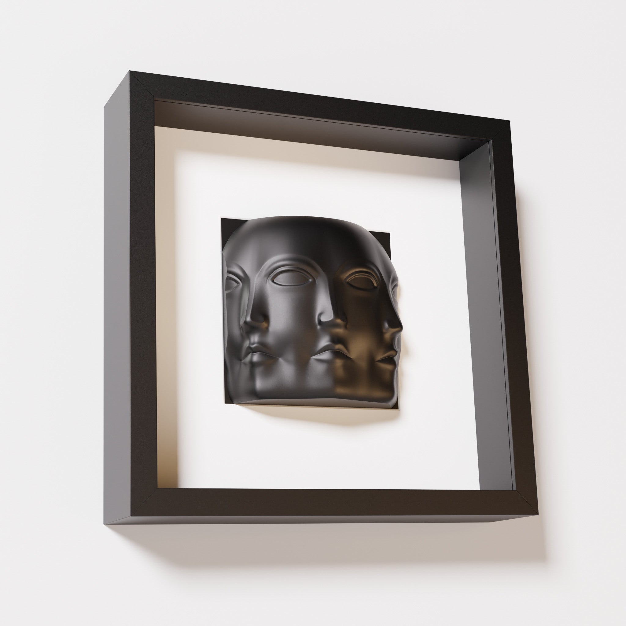 A close-up of a black shadowbox frame containing a matte black sculpture of 'Dora,' featuring three interconnected faces merging at the edges, creating a surreal and multi-dimensional effect.