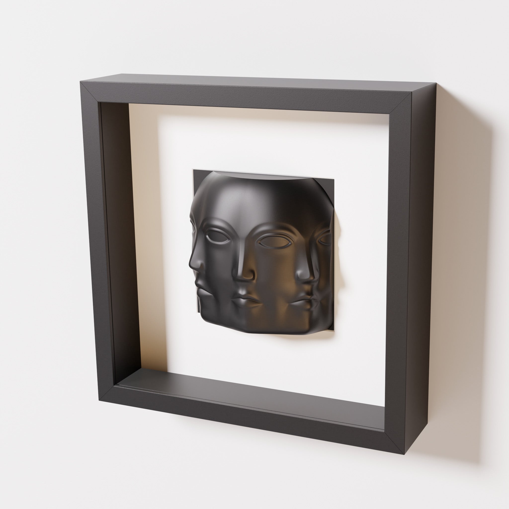 A close-up of a black shadowbox frame containing a matte black sculpture of 'Dora,' featuring three interconnected faces merging at the edges, creating a surreal and multi-dimensional effect.