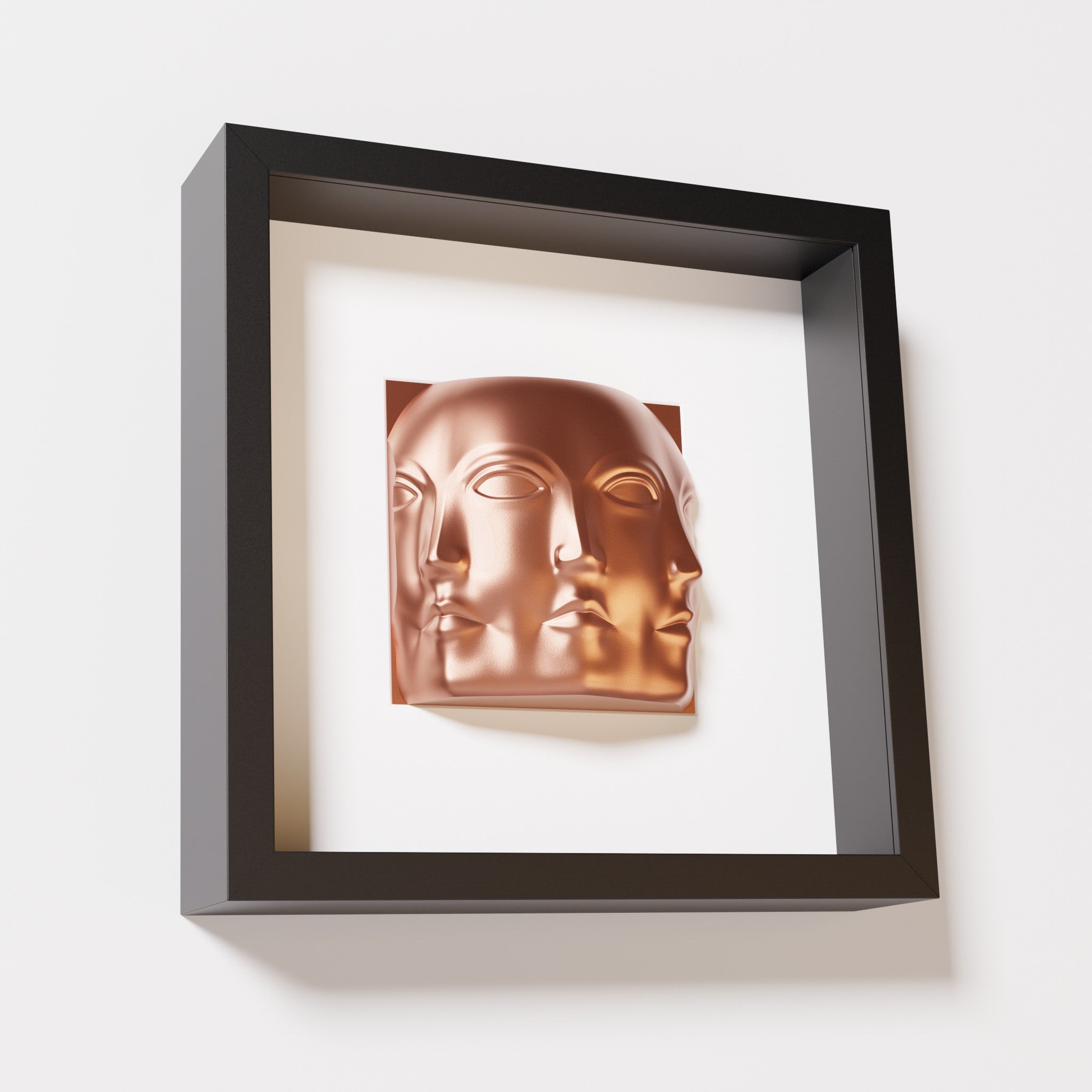 A close-up of a black shadowbox frame containing a chrome copper sculpture of 'Dora,' featuring three interconnected faces merging at the edges, creating a surreal and multi-dimensional effect.